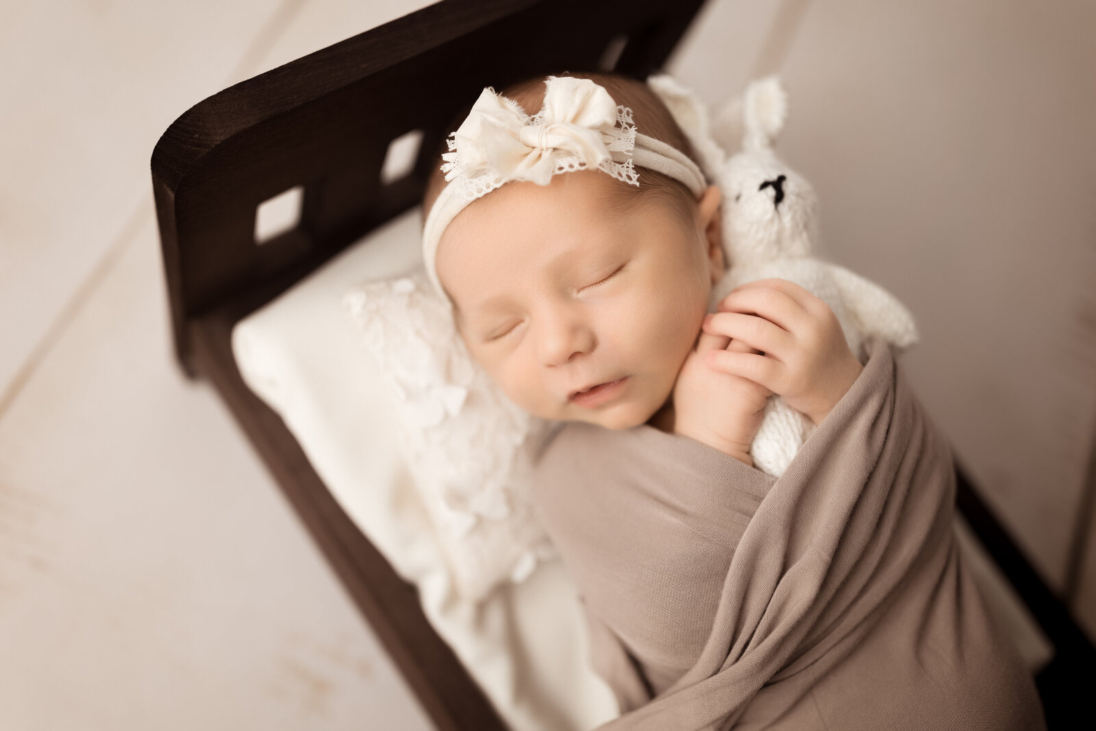 newborn baby girl holds knit rabbit in  baby bed in  studio near Birmingham