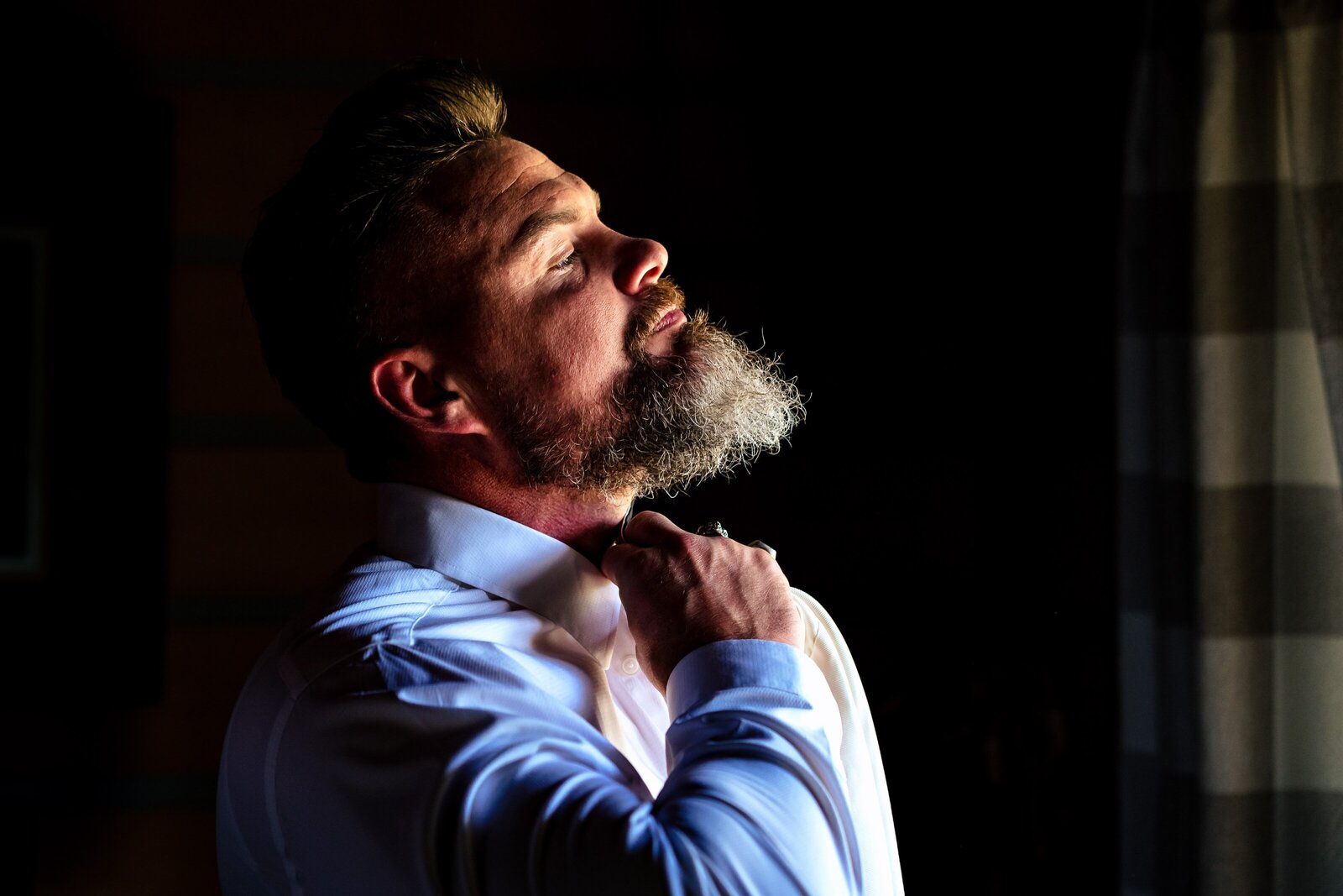 creative wedding photo of a bearded groom tying his tie