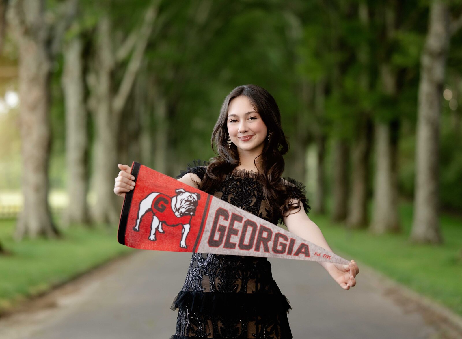Teen girl holding GA bulldog pendant as she was happy at being accept to UGA. Graduation photos taken at Berry College, outside of Atlanta, GA.