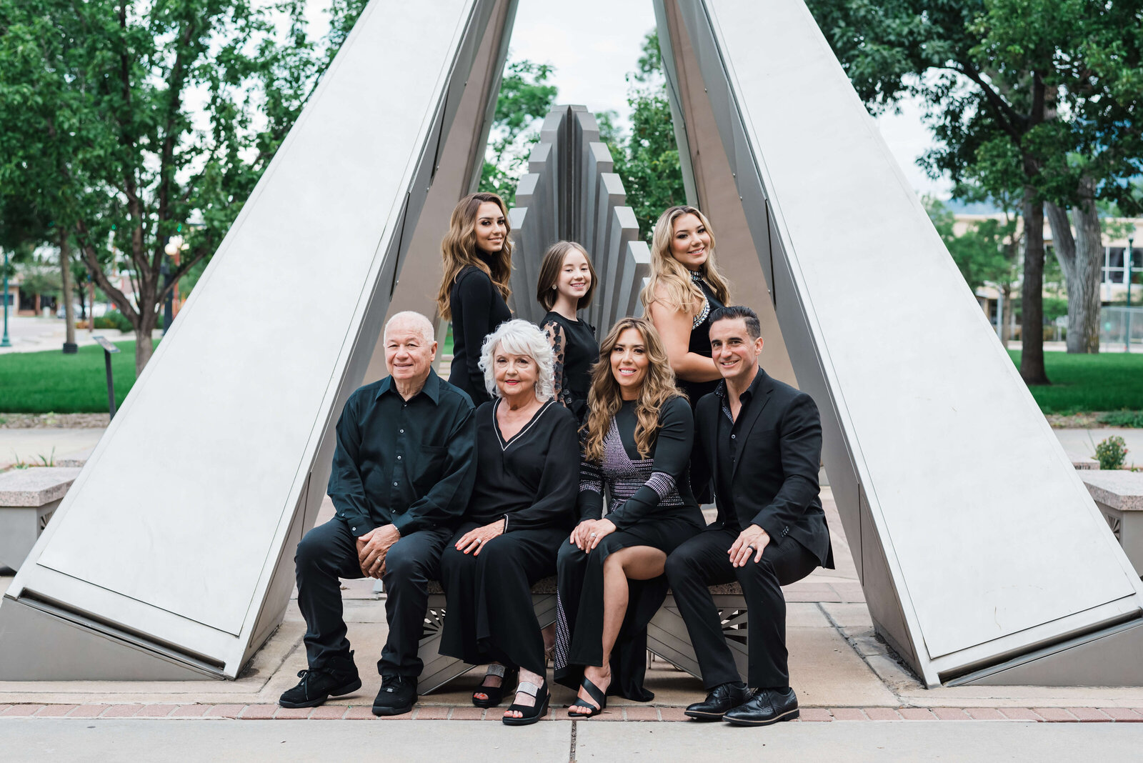 Northern Virginia family photographer takes a formal photo of an adult family, including grandparents, while they sit in front of an art statue