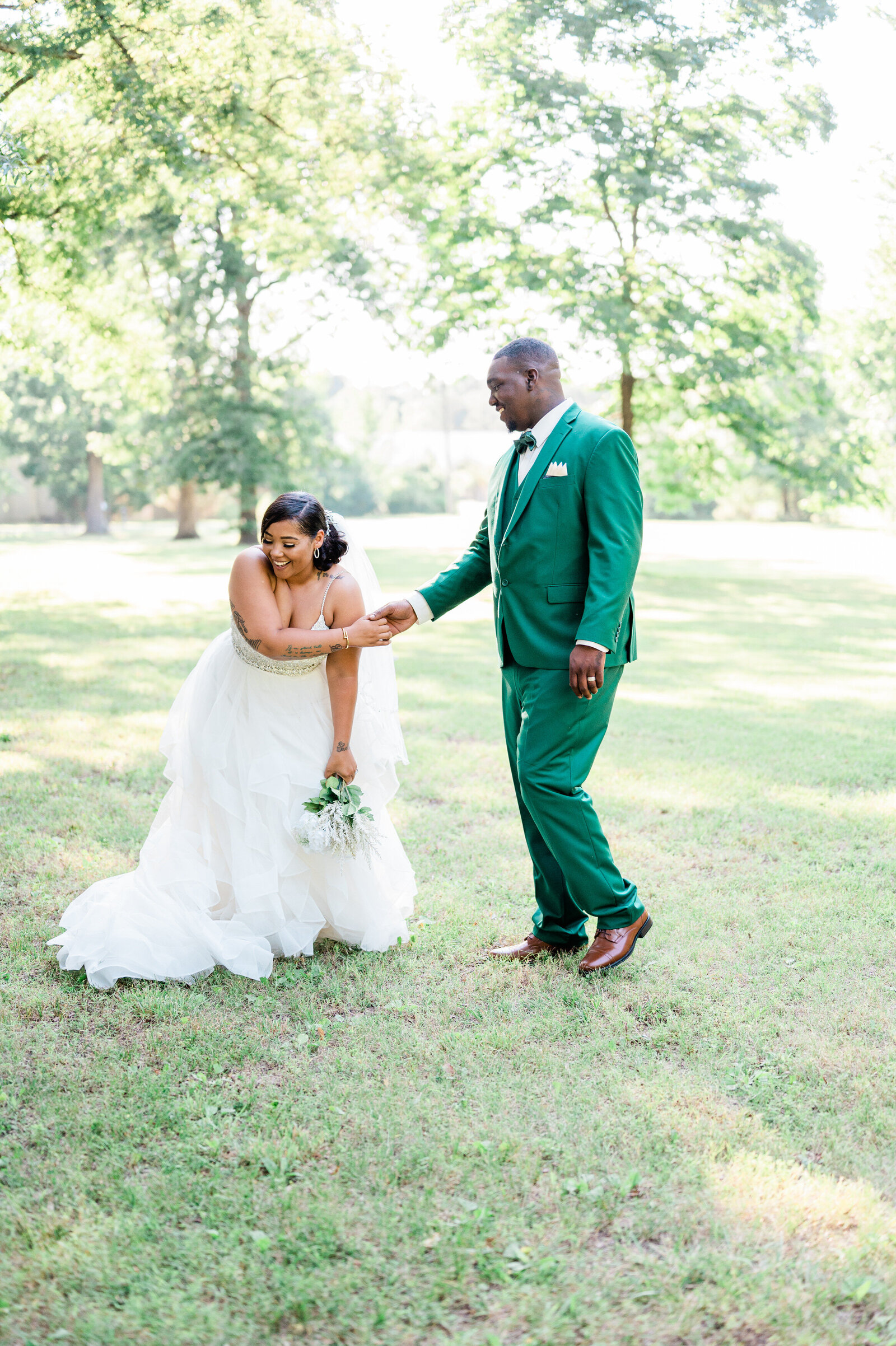 A newlywed couple holding hands as one leans over laughing
