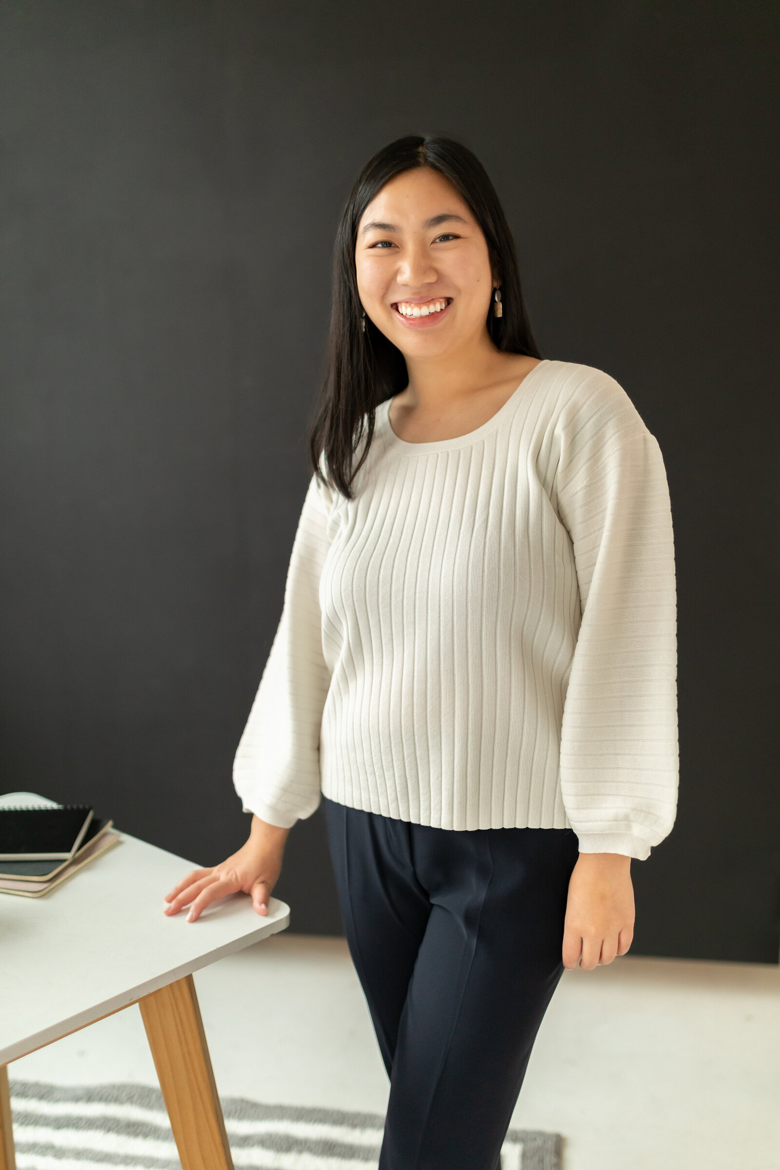 woman stands with hand on desk against black wall during branding session at studiostudio in ann arbor michigan