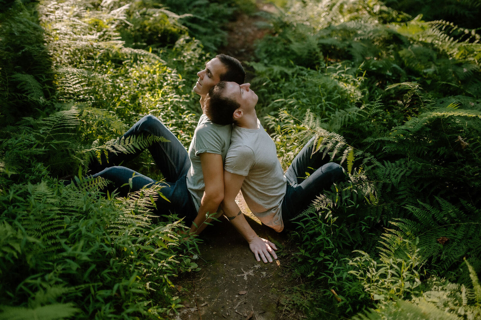 couple sitting in lush green enchanted forest back to back peaceful moment
