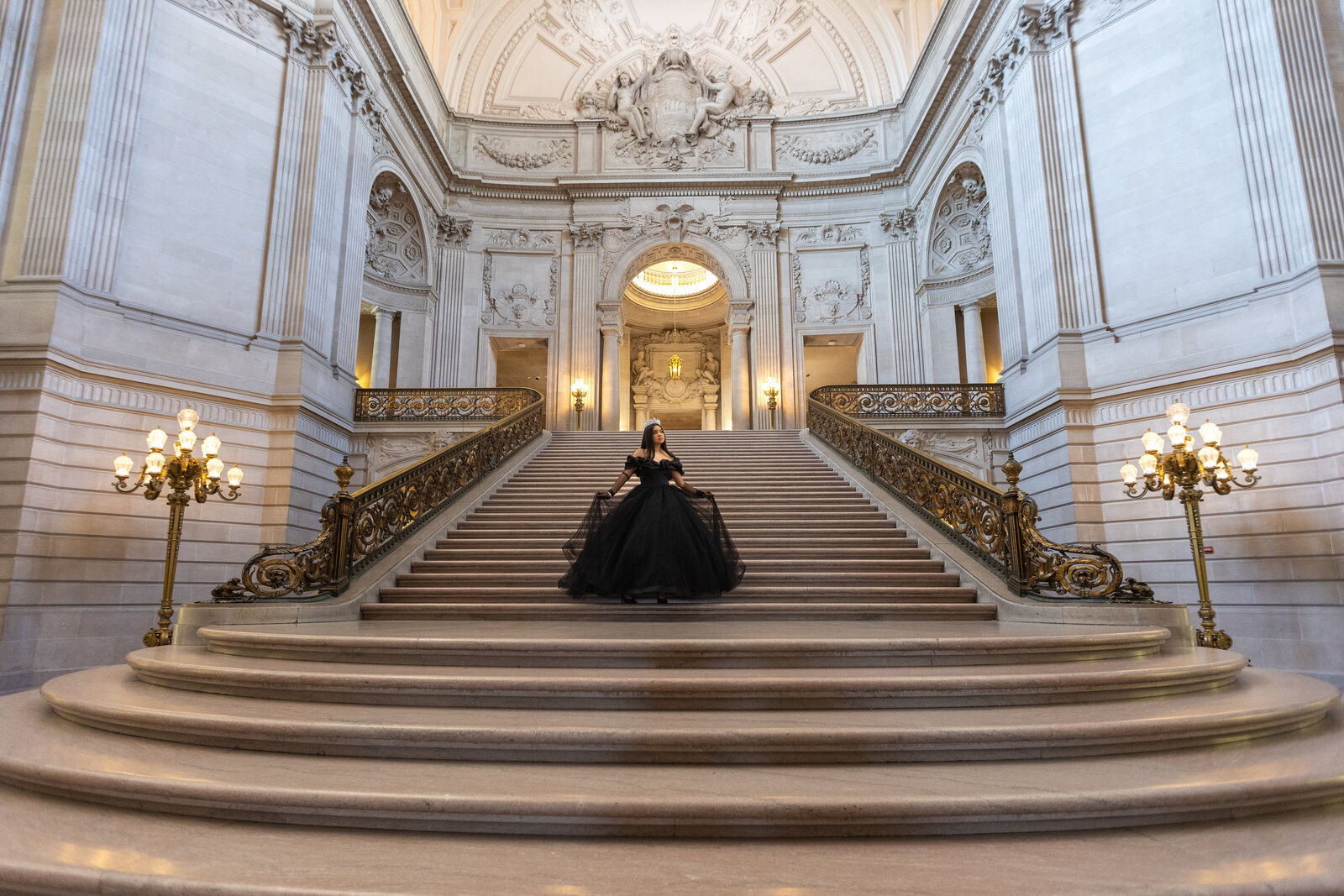 A Quinceañera photoshoot in San Francisco City Hall of a young girl in a black quince dress in the middle of the staircase.  Photo by Philippe Studio Pro, a Sacramento wedding photographer.