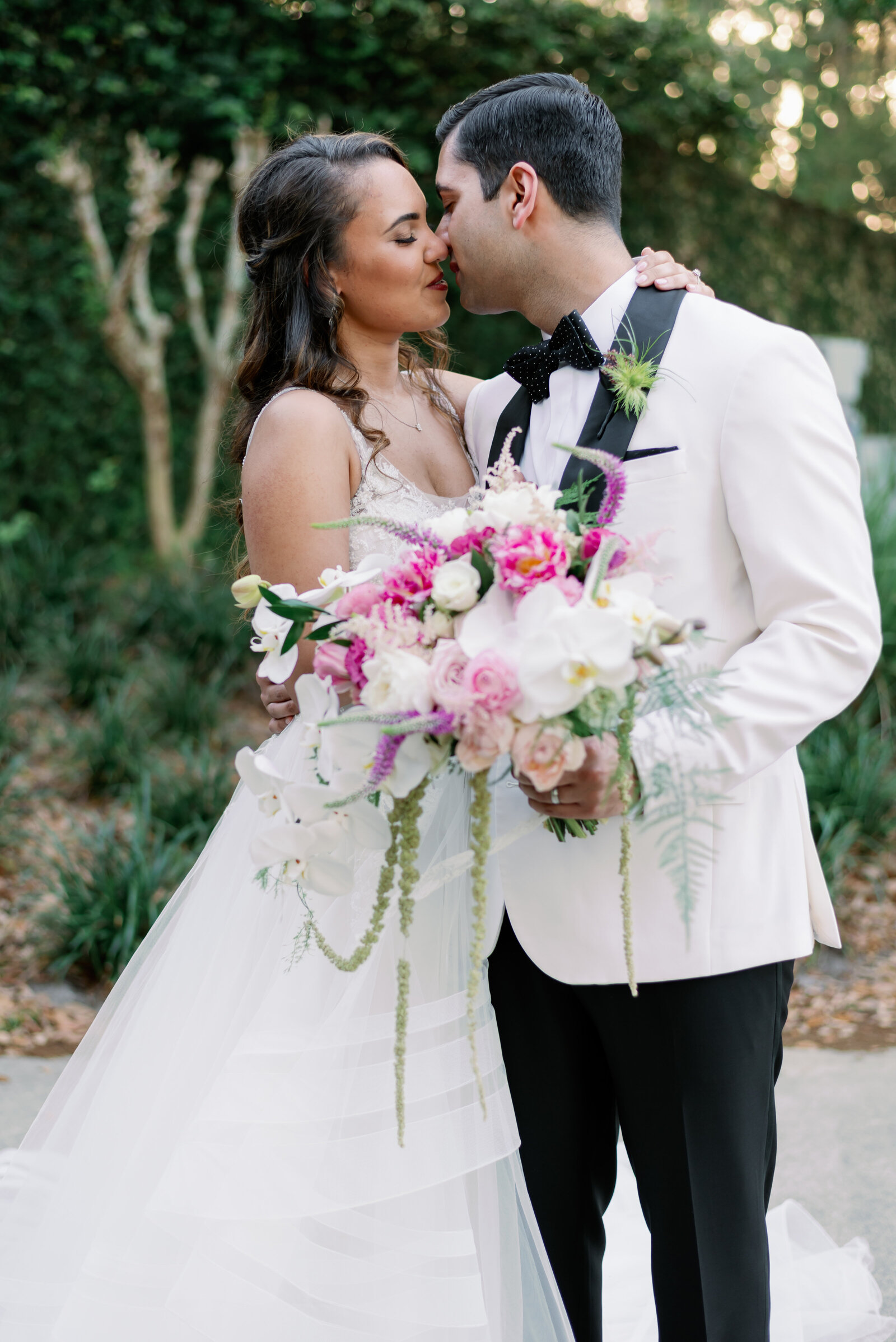 bride and groom close together in an embrace kissing tenderly and holding the wedding bouquet