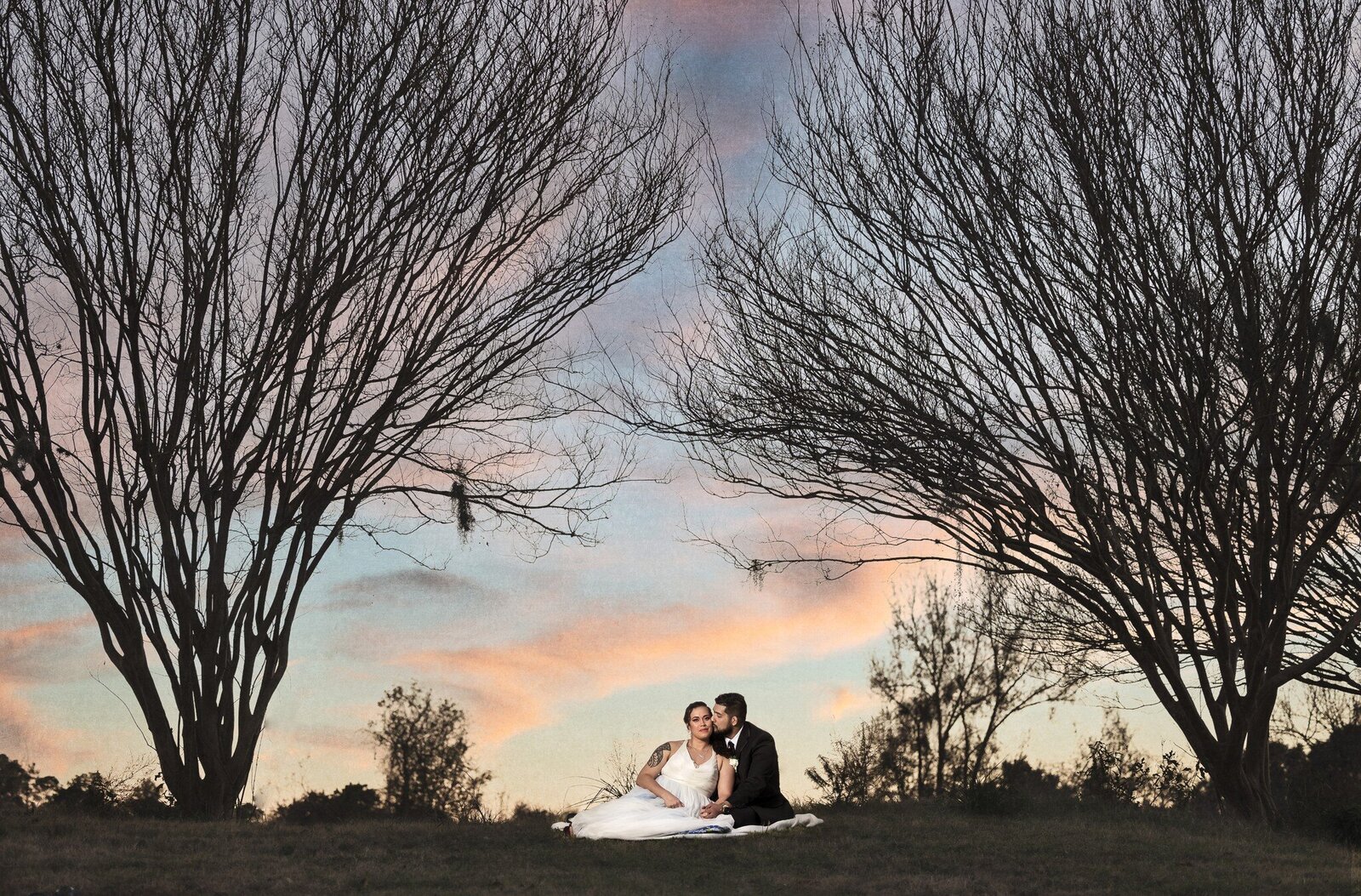 bride and groom sitting on field in fall
