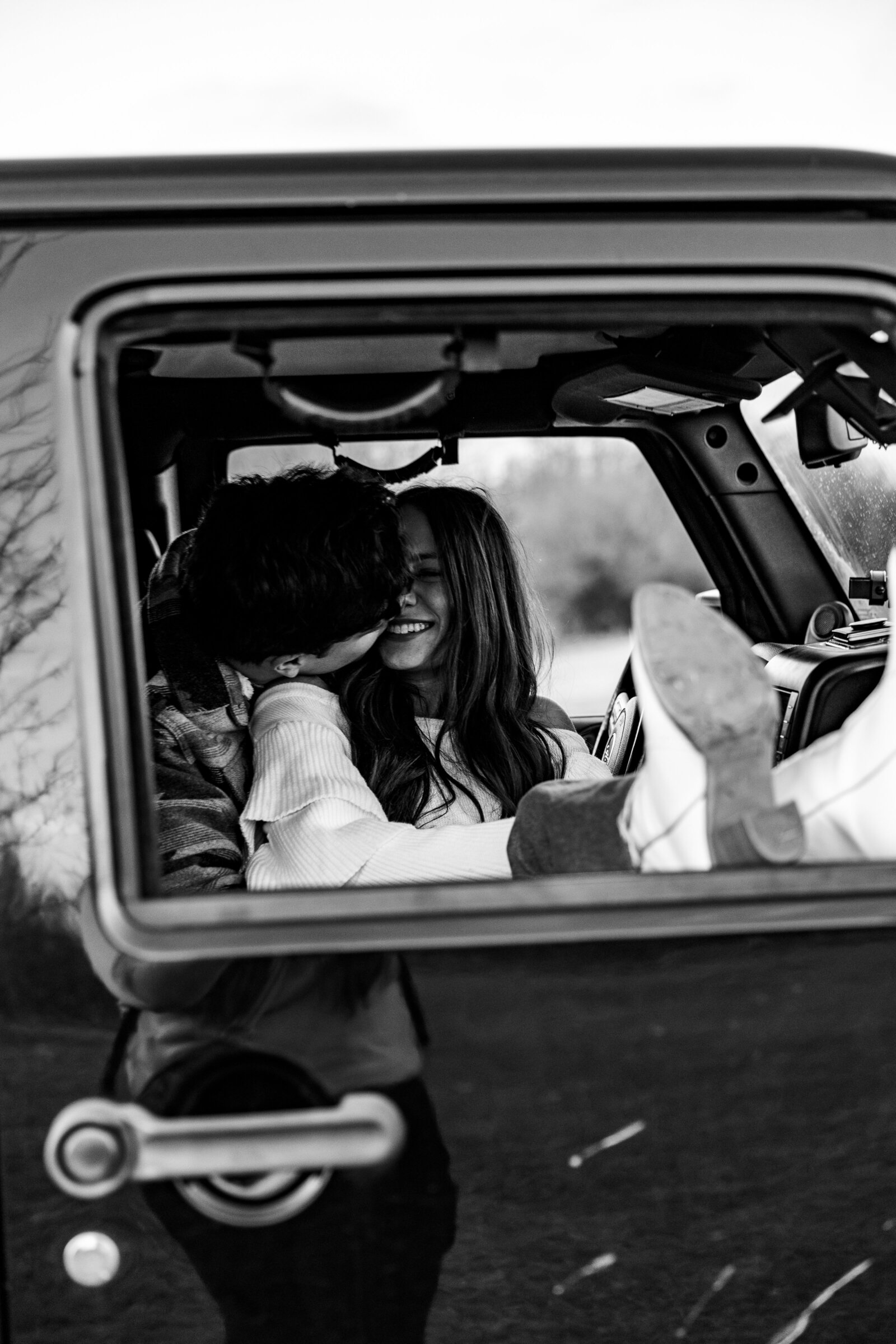 Black and white shot of a couple cozying up in the front seat of their Jeep at Shelby Farms Park in Memphis.
