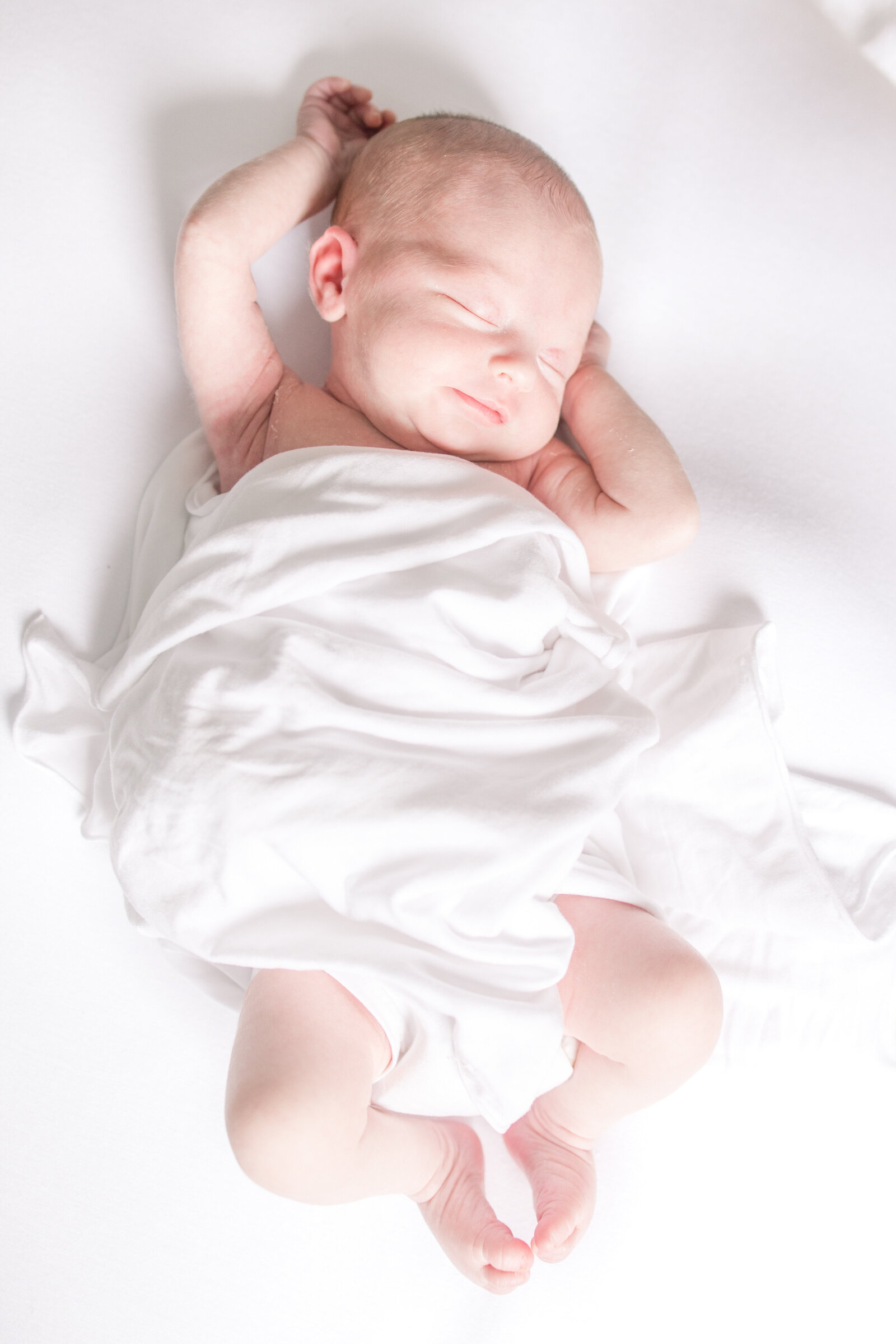 newborn-baby-stretching-in-white-swaddle