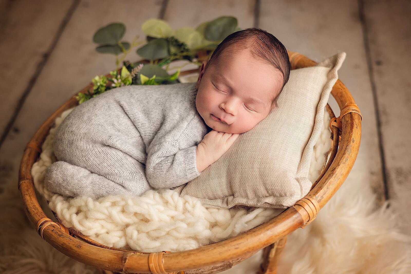 Newborn baby peacefully sleeping in a woven basket, captured by Bia Schaefer, Orlando's expert in in-home newborn photography.