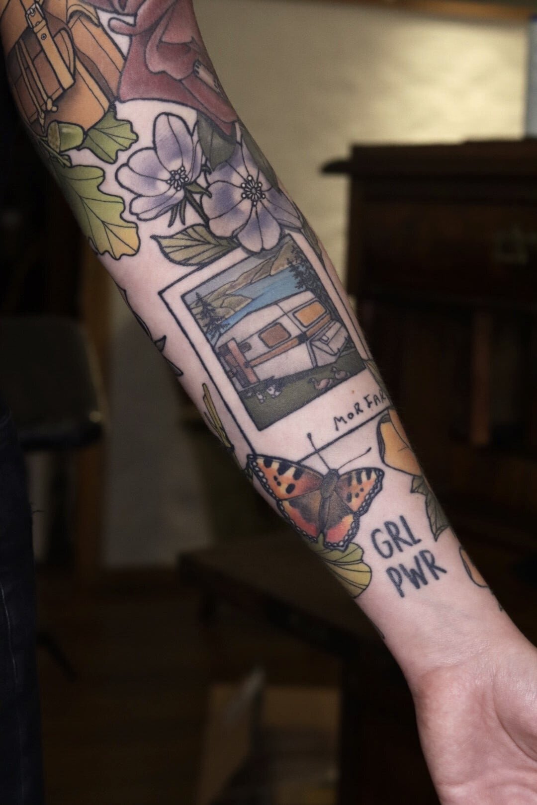 Neo traditional tatuering av husvagn, polaroid, fjäril och blommor.