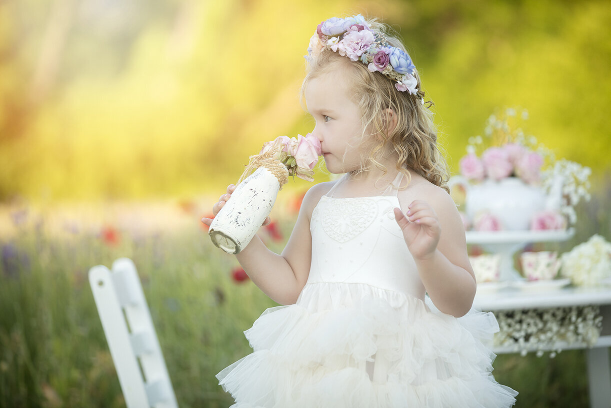 Little girl smelling flowers at tea party,  Dallas child photographer.