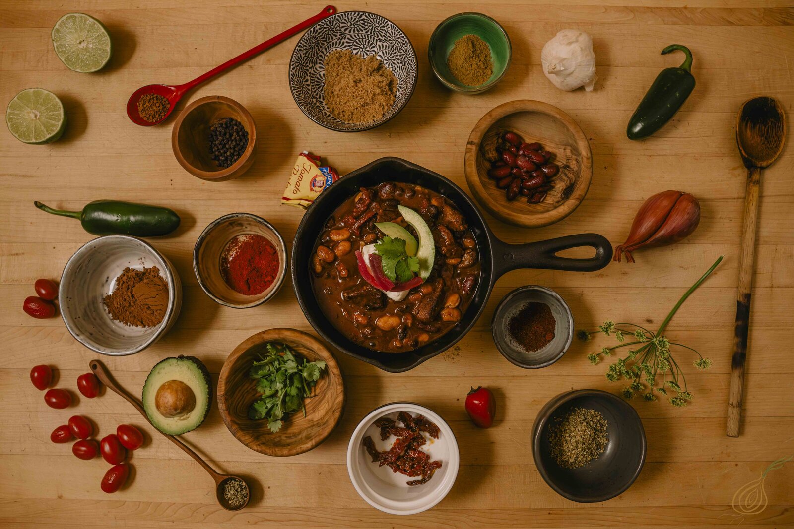 A vibrant bowl of chili with an assorted ingredients displayed on a rustic table.