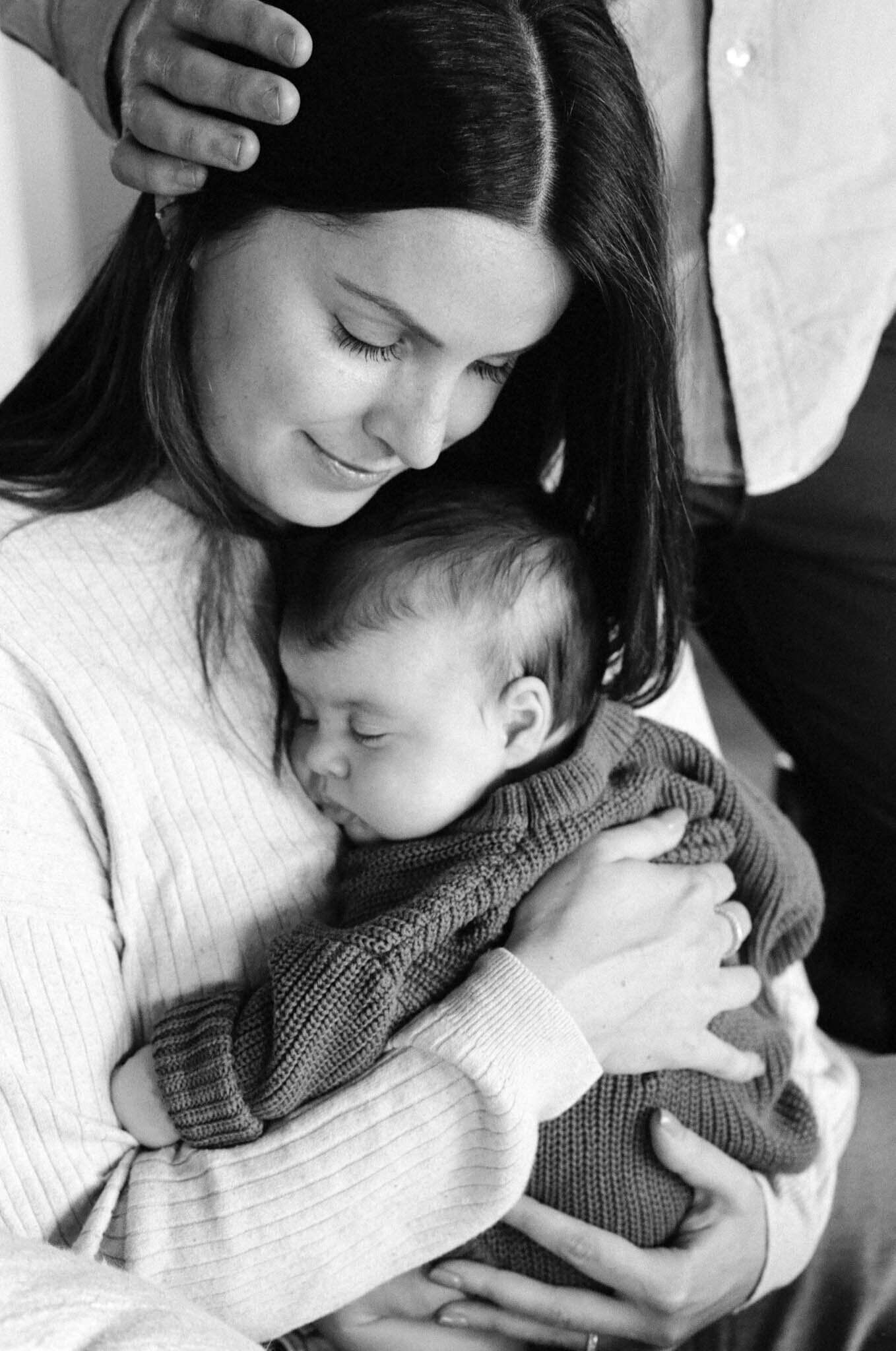 Closeup of mother hugging newborn sleeping child in her Portland, Oregon home.