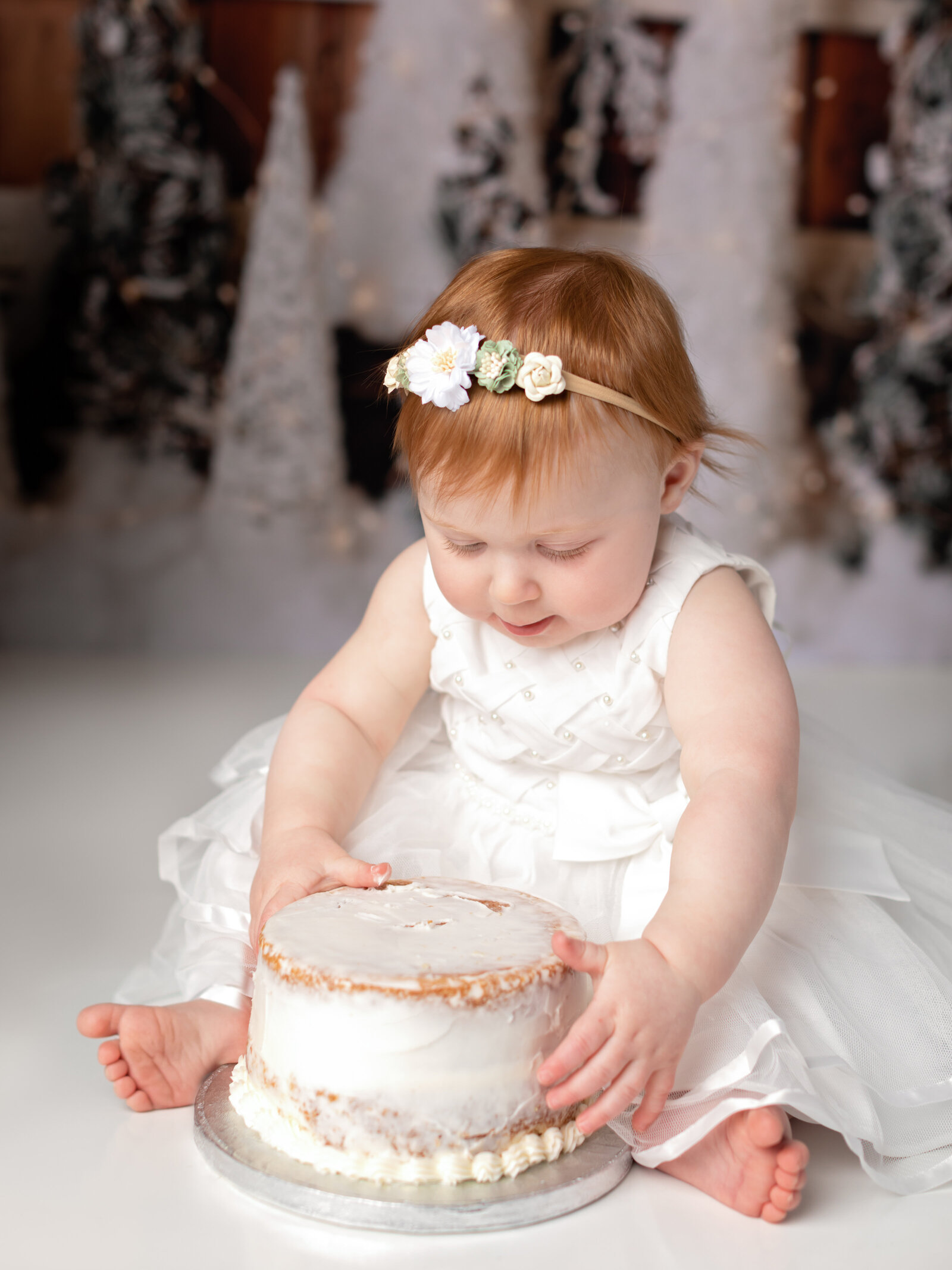 one year old girl smashing cake for birthday photoshoot