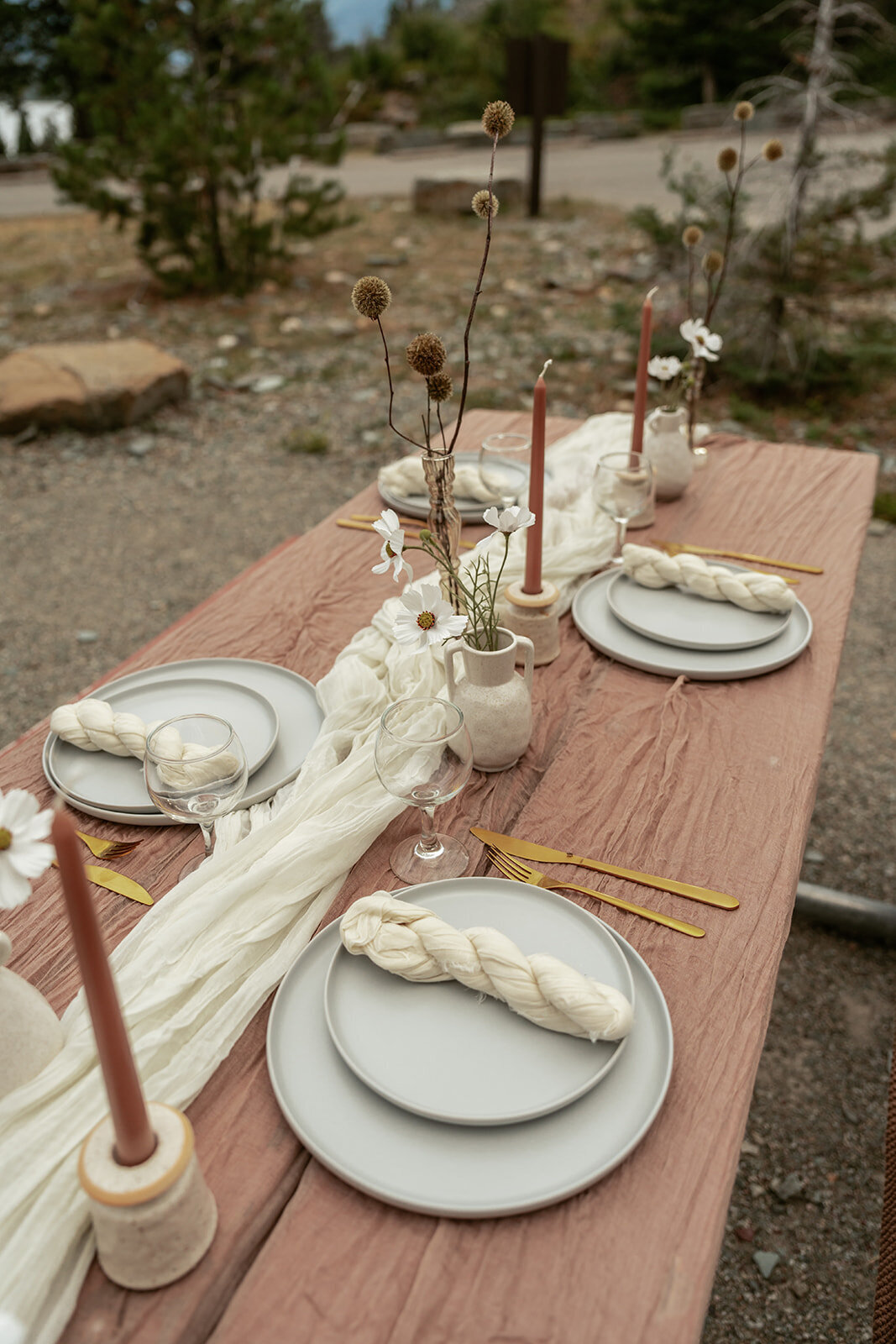 A simple, modern elopement tablescape featuring clay vases, neutral linens, and soft candlelight for a cozy and refined outdoor celebration.
