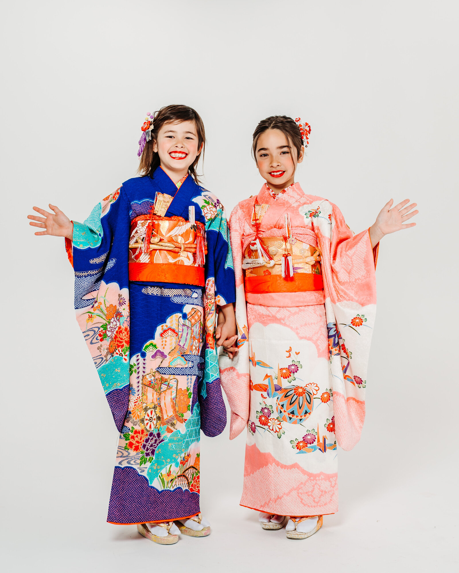 Two young girls in vibrant formal kimono posing for a Shichi-Go-San studio photo | 七五三 記念 華やかな着物姿の女の子2人 スタジオ写真
