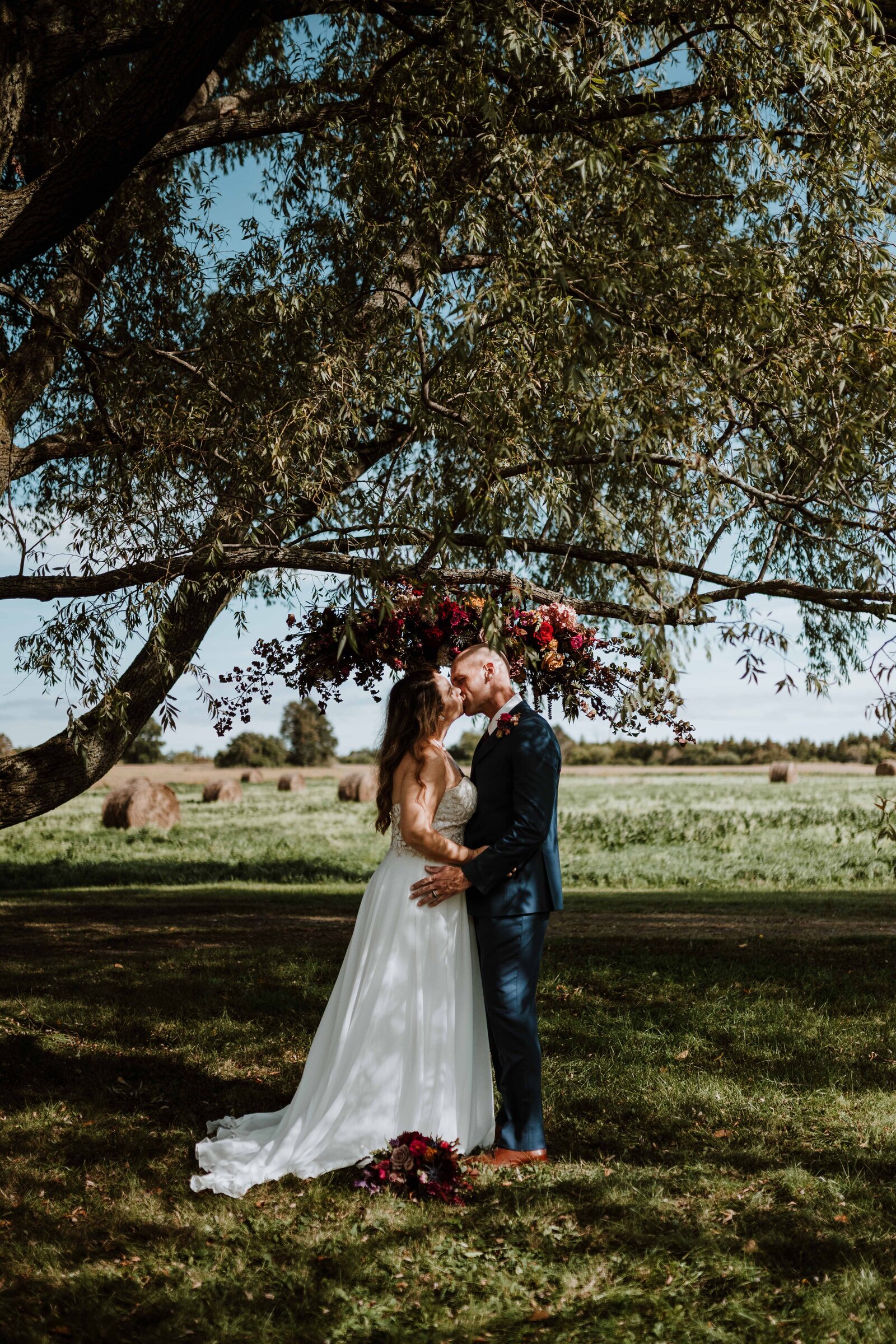 Newlyweds kissing under a large tree