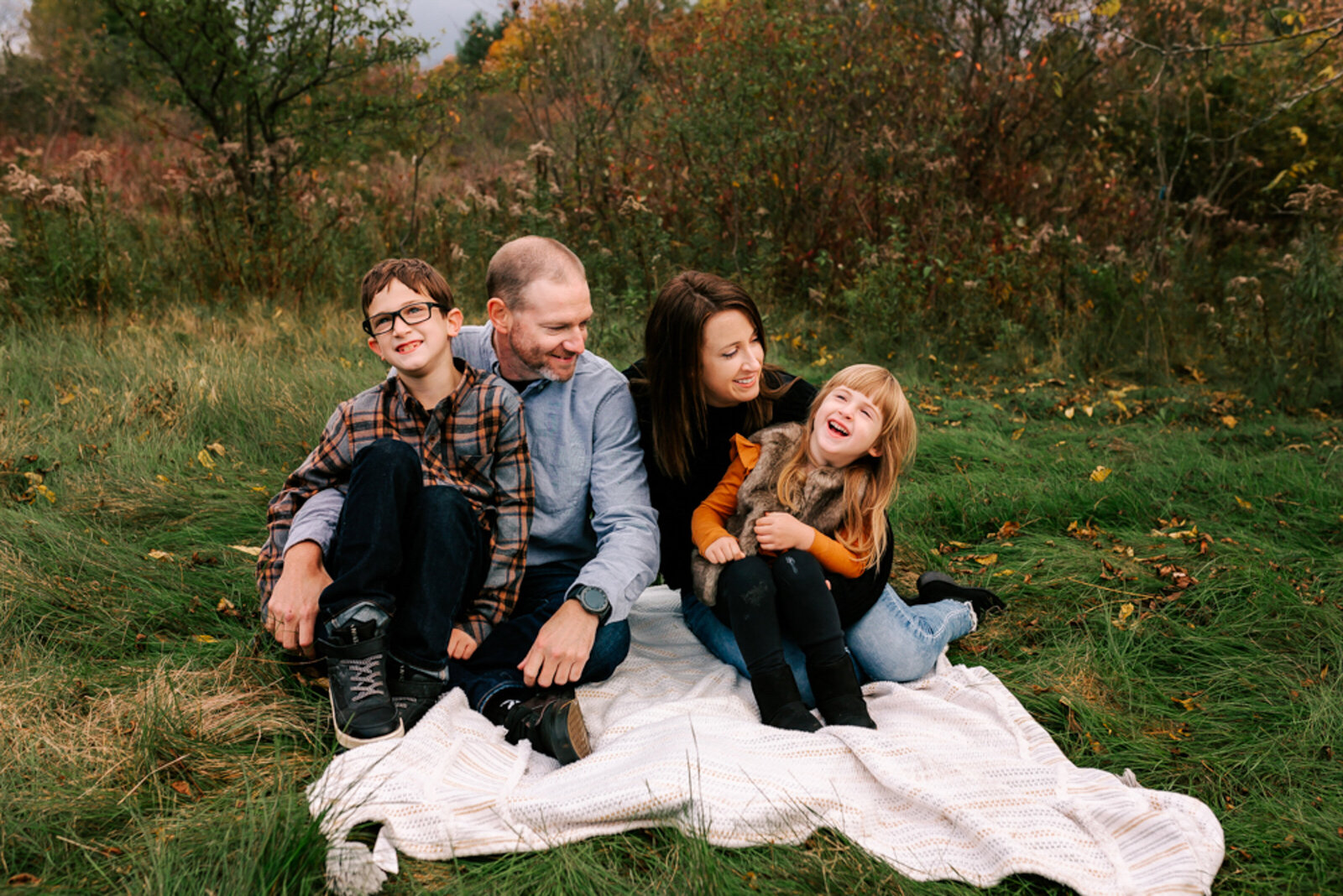 A sweet little family giggles on a white blanket during their family photos