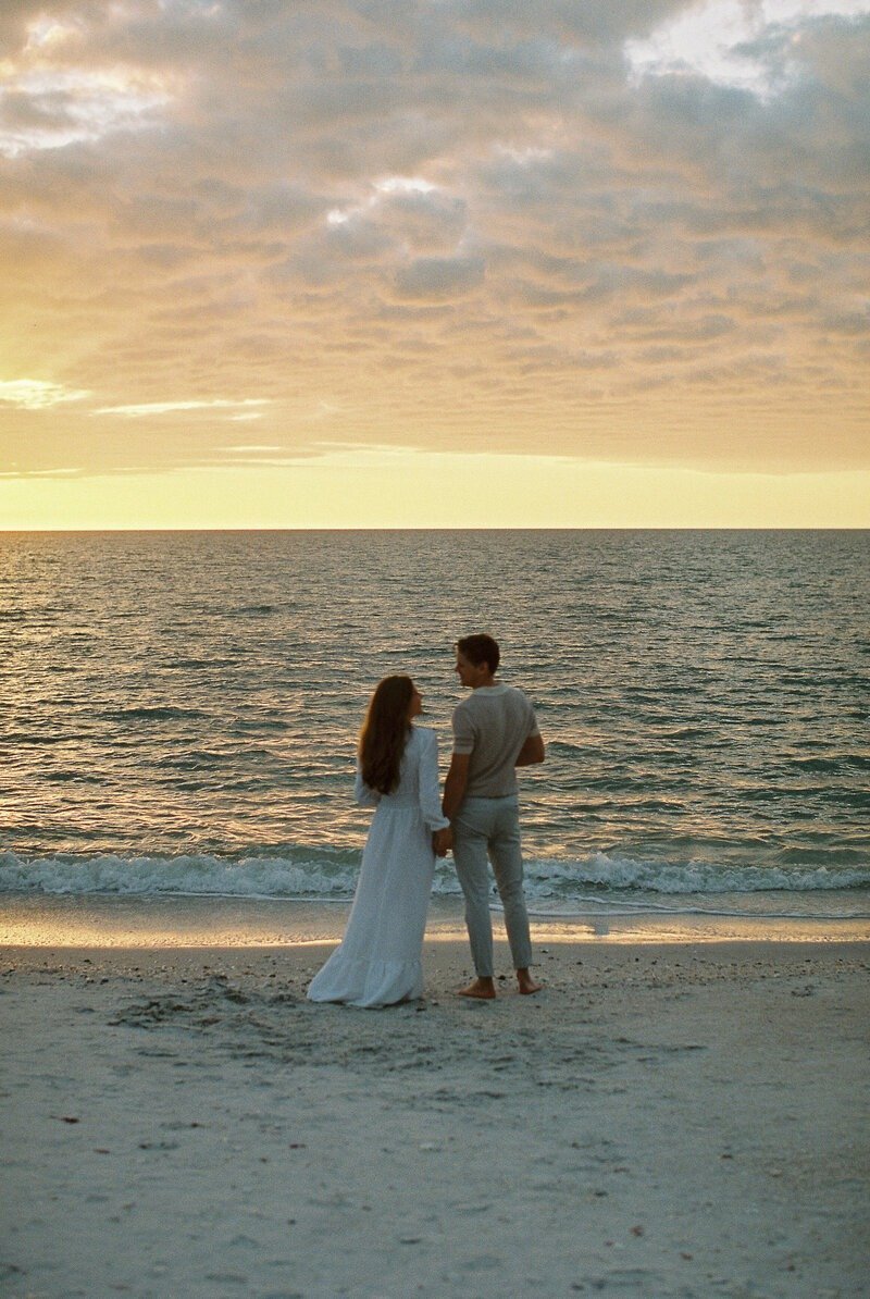 couple holding hands at sunset on Naples beach