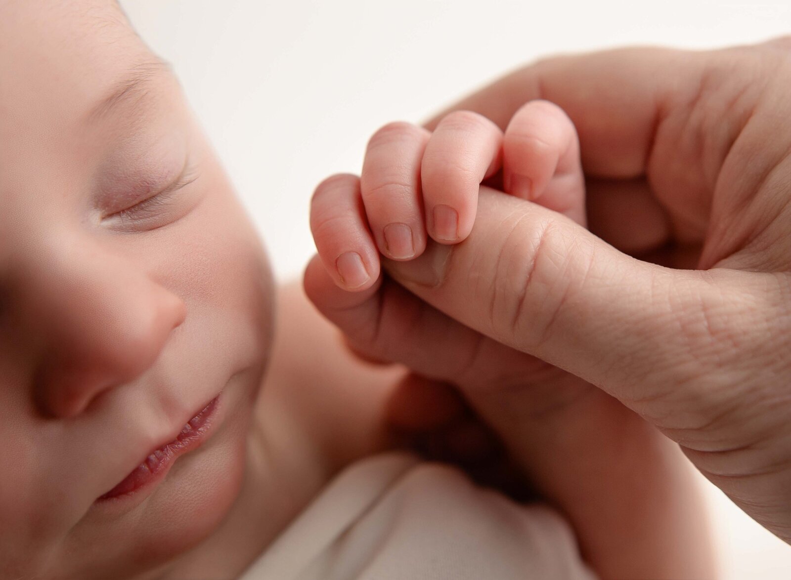 Macro newborn photography of baby holding mom's thumb. Photo by Jenni Nikki Photography, Marietta Newborn photographer.