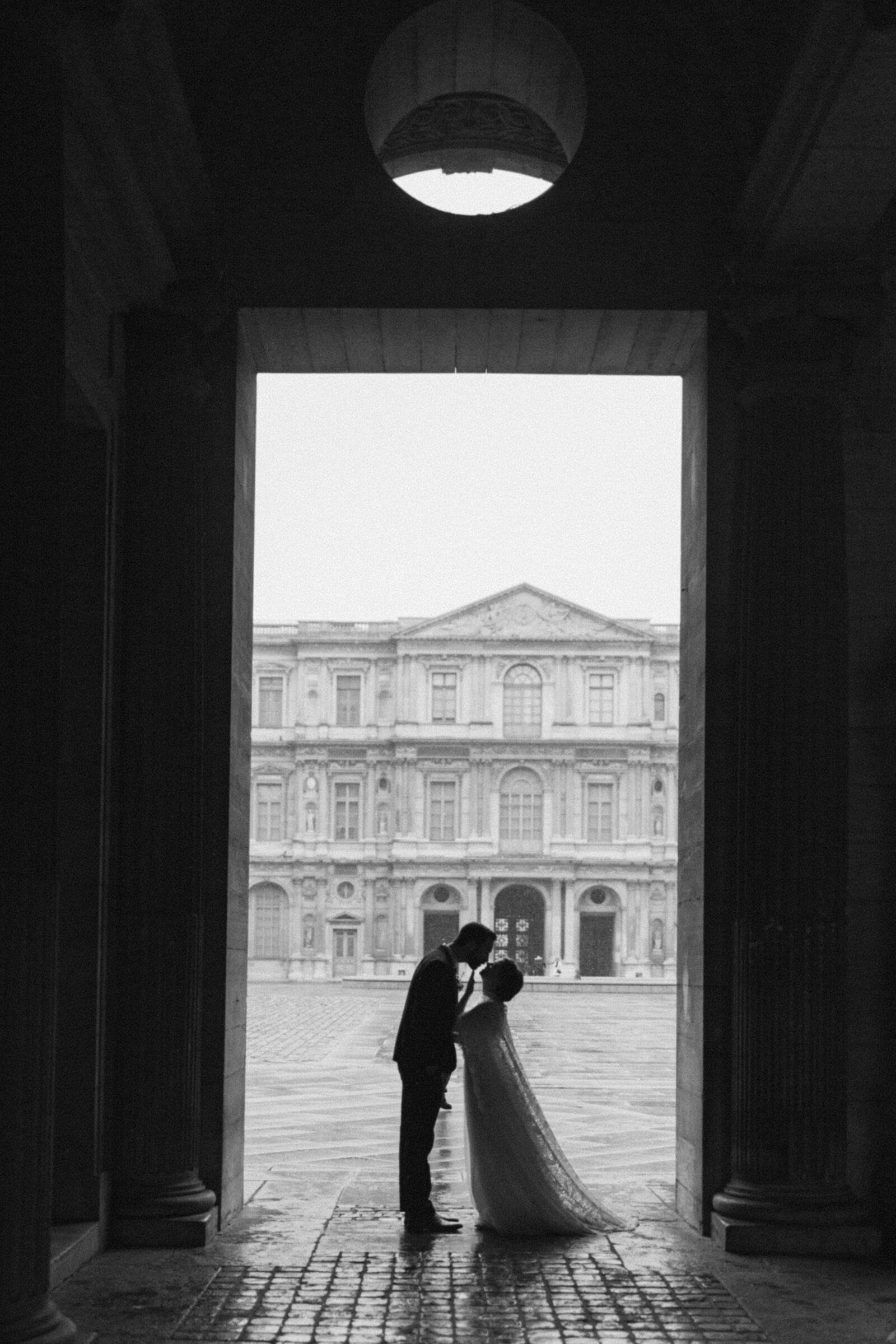 black and white photo of bride and groom kissing in silhouette at the louvre