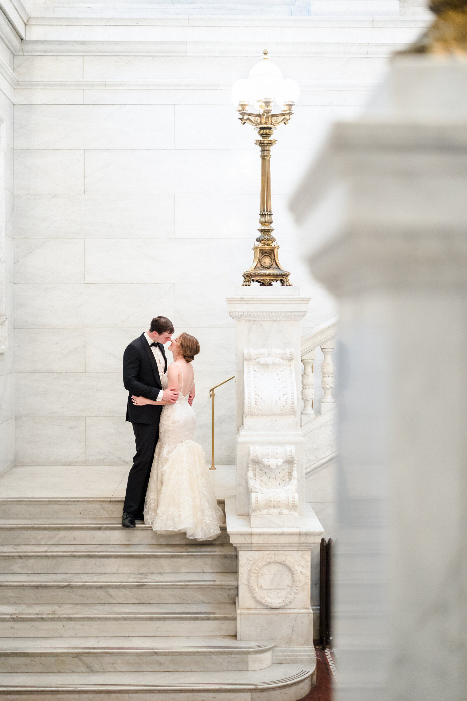 A bride and groom lean in for a kiss on the steps inside of the Ohio Statehouse