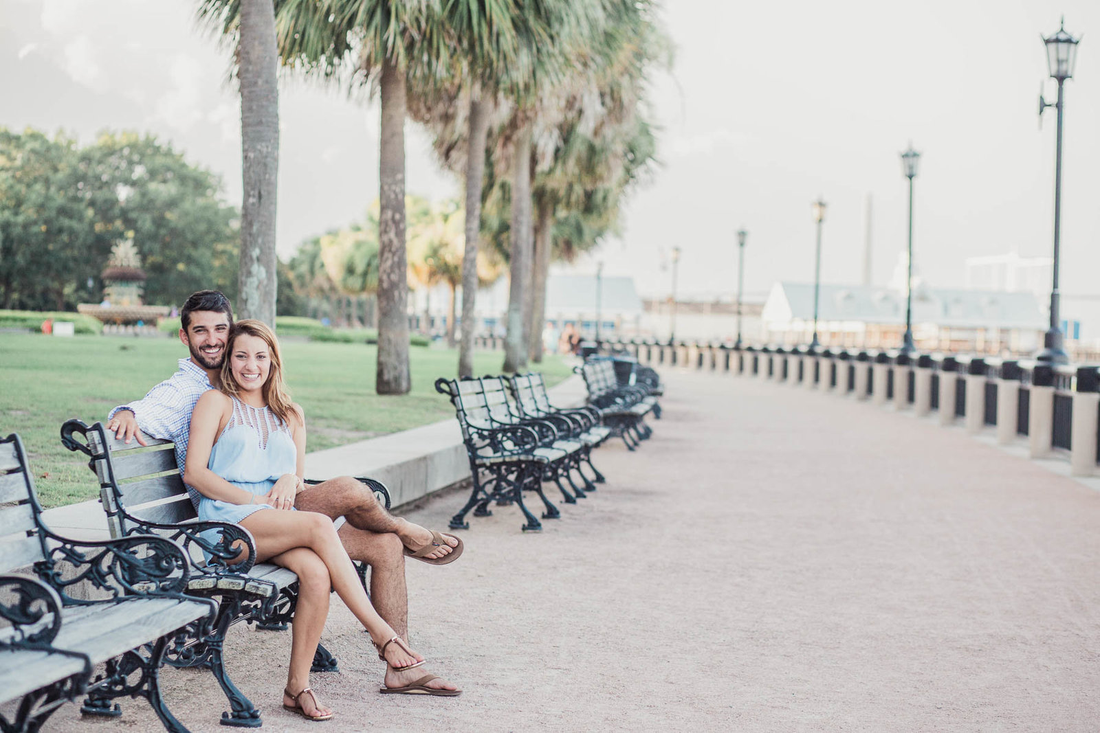 Engaged couple sits on a bench, watching the ocean, Waterfront Park, Charleston, South Carolina
