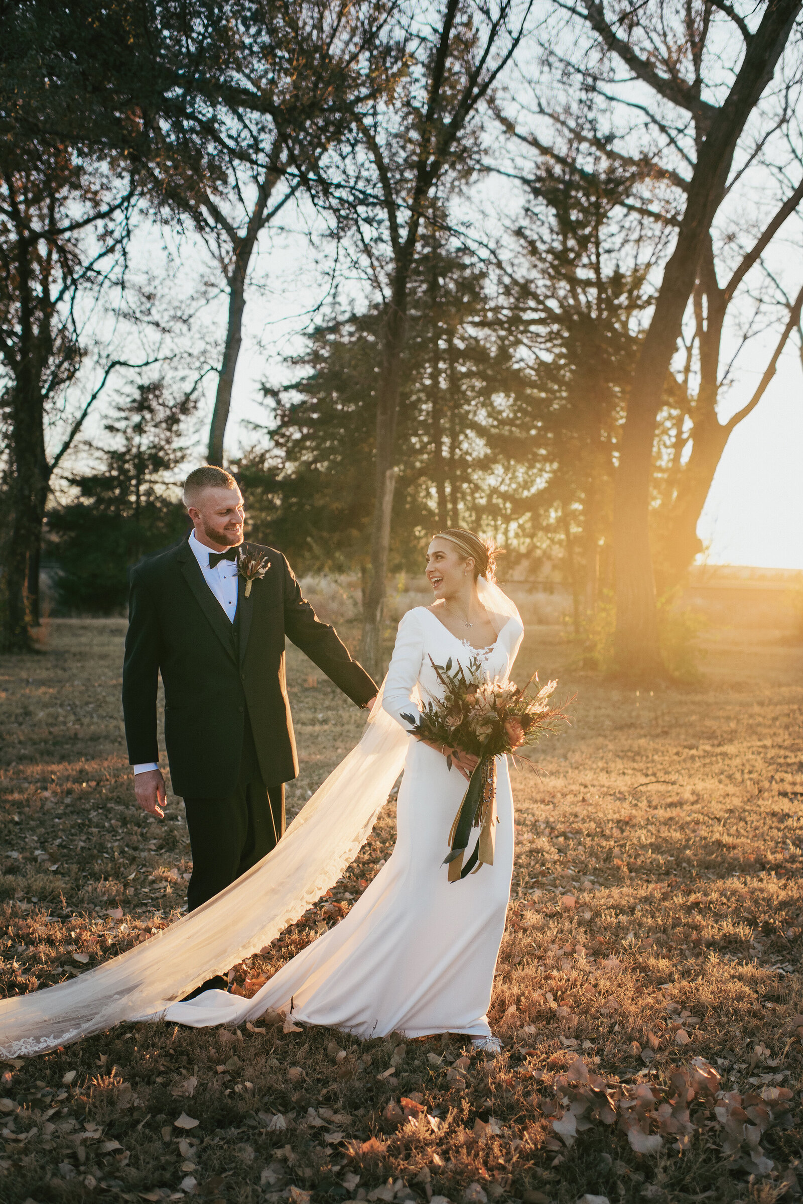 bride and groom walking into the sunset holding hands with the sun shining on them