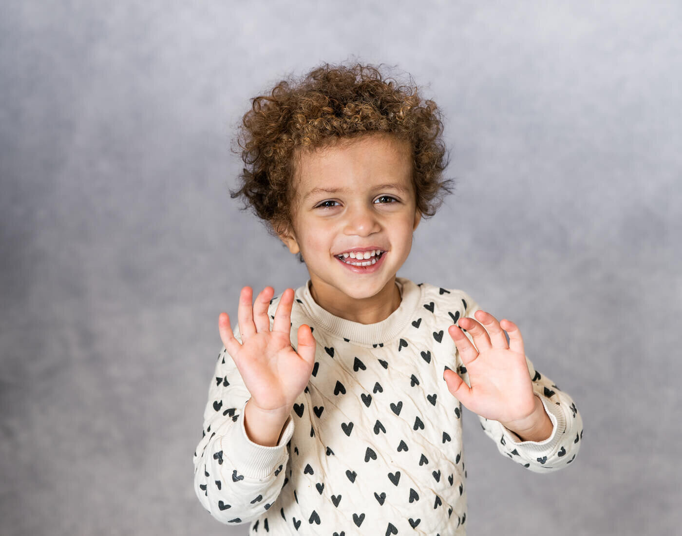 A kid poses with their hands up.