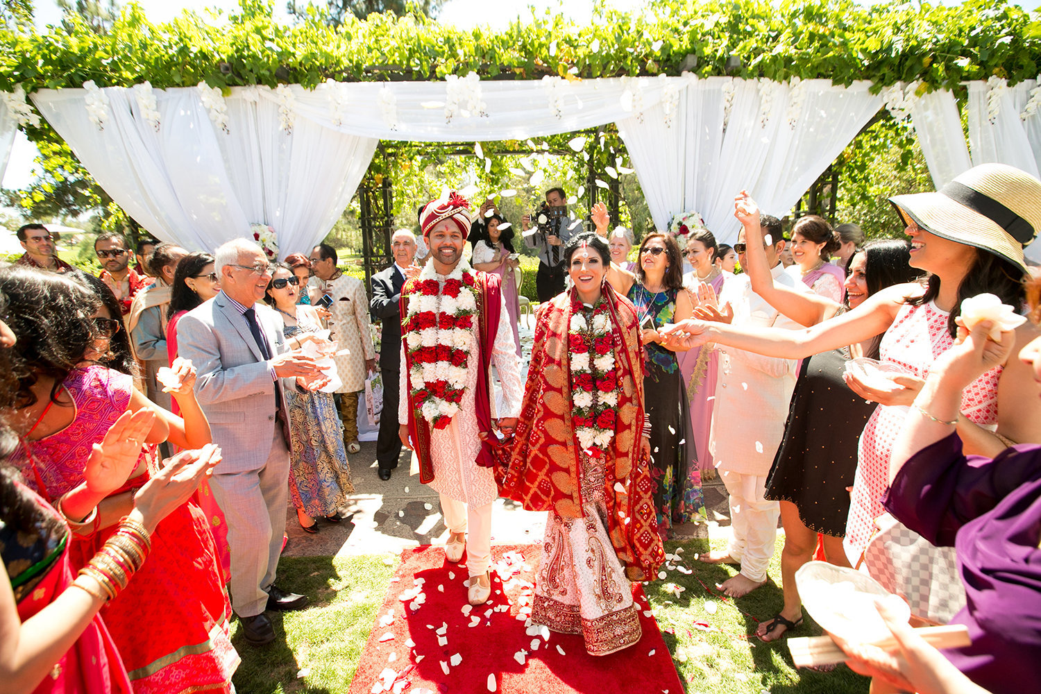 Bride and groom are showered with flower petals and rice after their Hindu wedding ceremony