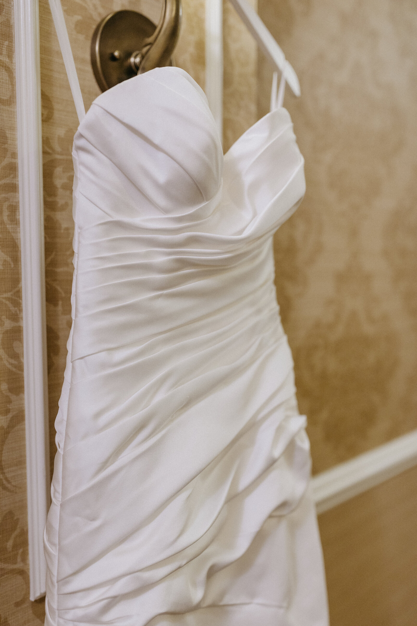 A wedding dress hangs on a light fixture on a hotel hallway