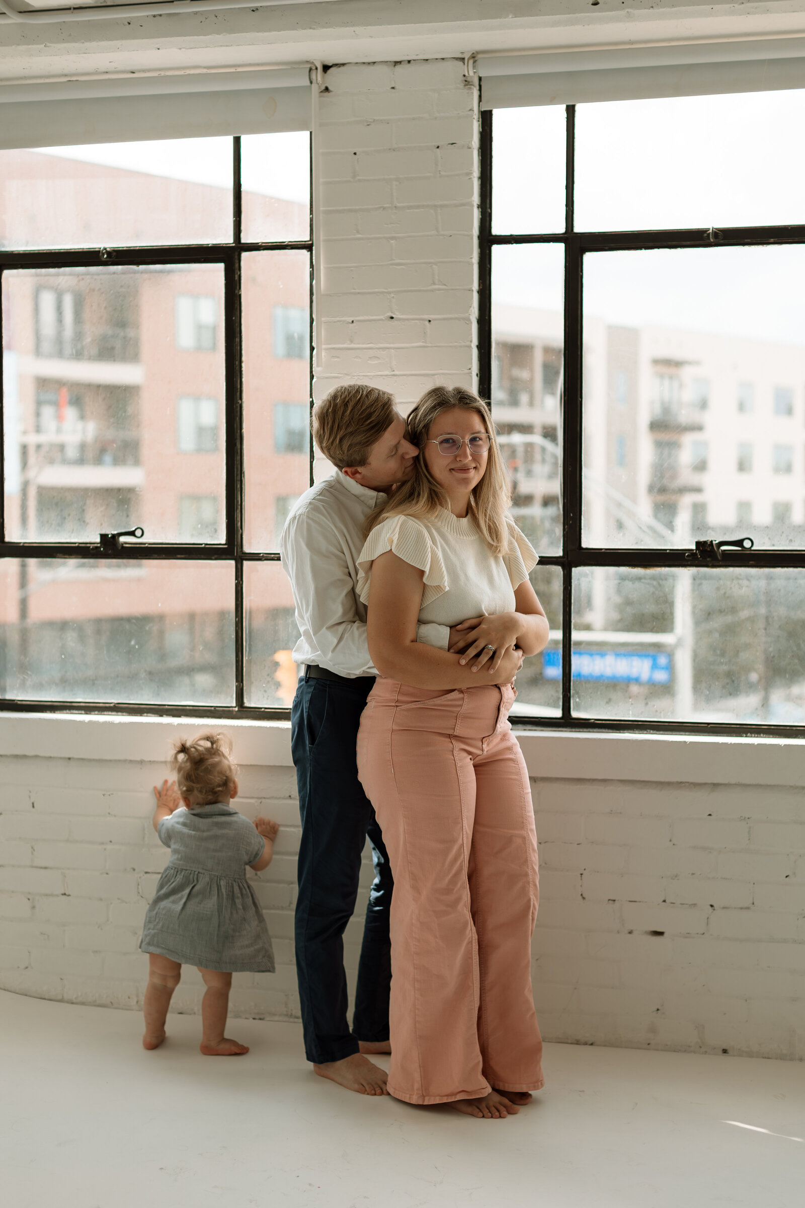 dad hugging mom while daughter looks out window