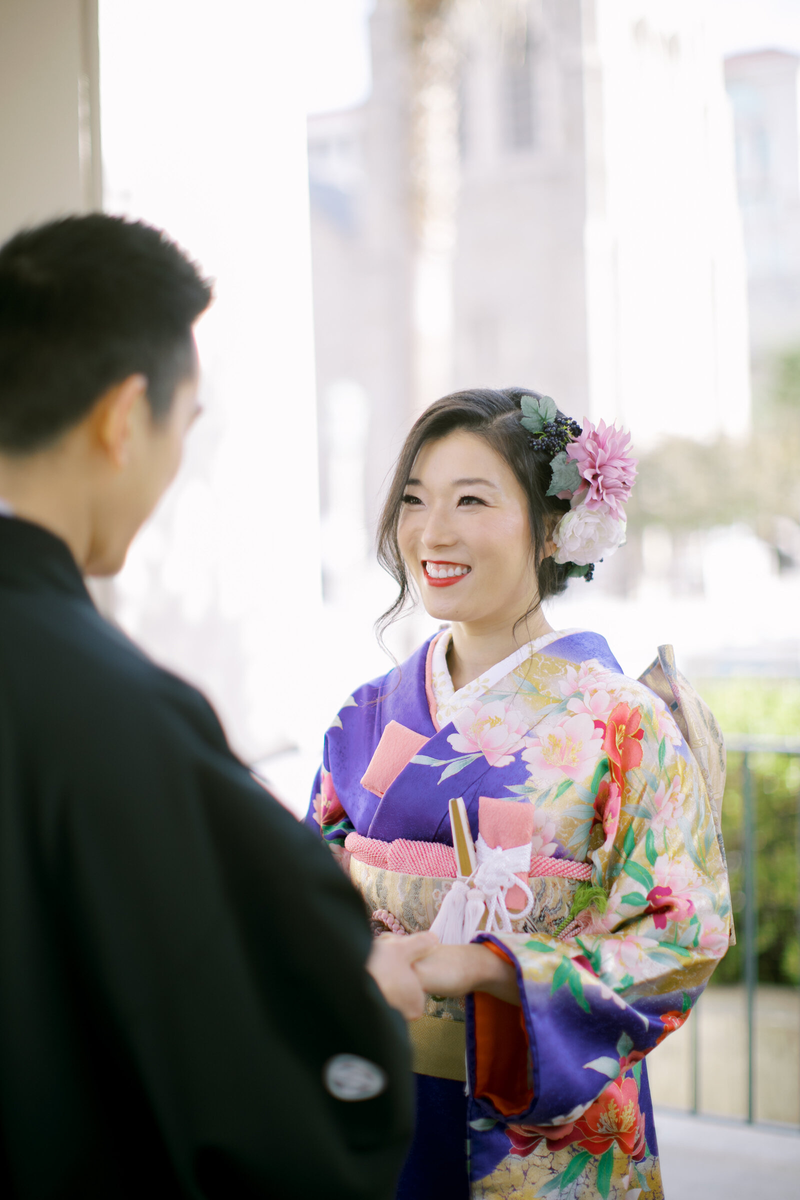 Close-up of bride in purple floral wedding kimono rental smiling at groom while holding hands at Pasadena City Hall, California | パサデナ市庁舎で新郎と手を取り微笑む紫色振袖の花嫁 着物レンタルウェディング