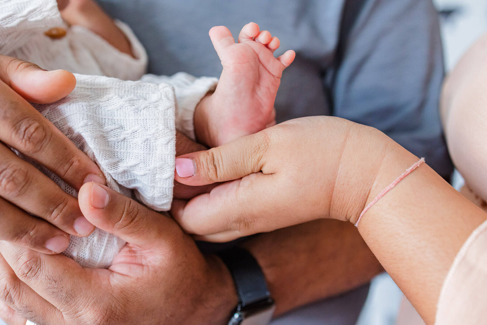 A close-up of a mom and dad holding their newborn son's little foot.