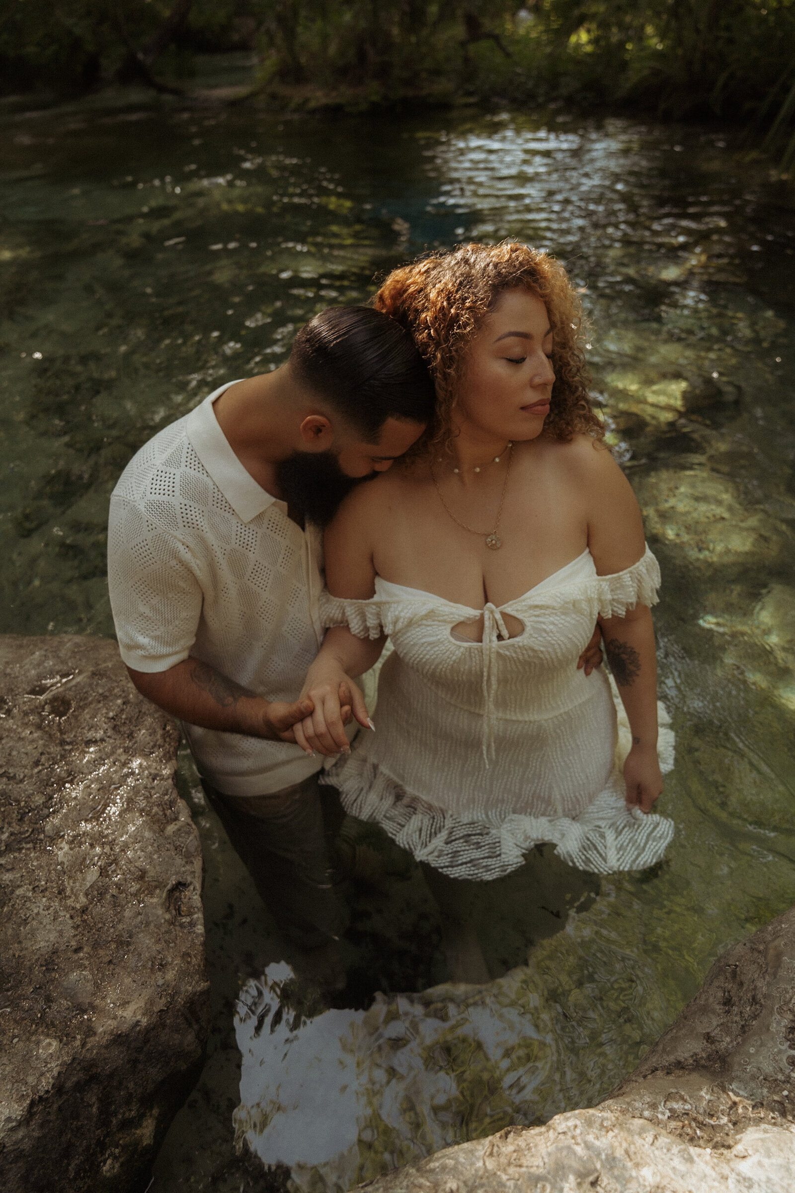 Romantic outdoor couple session in a natural spring, featuring a boho-style dress and serene embrace in the water.