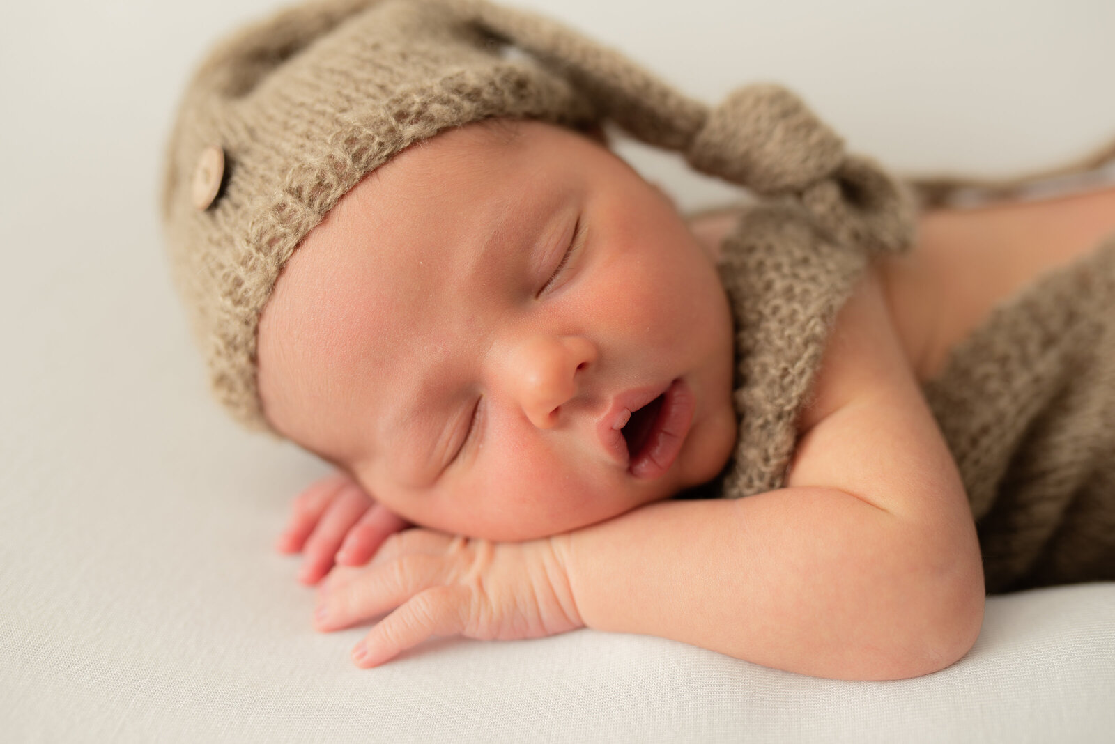 Newborn with brown knit slouchy hat and romper