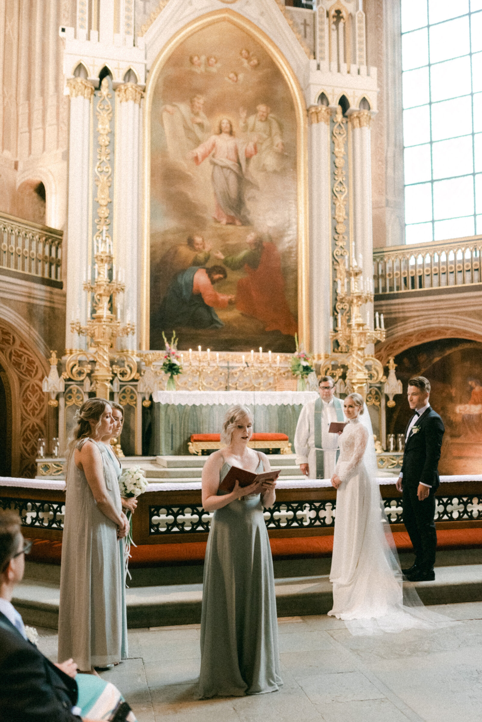Wedding couple on the altar and maid of honour reading bible during the ceremony in Turku cathedral