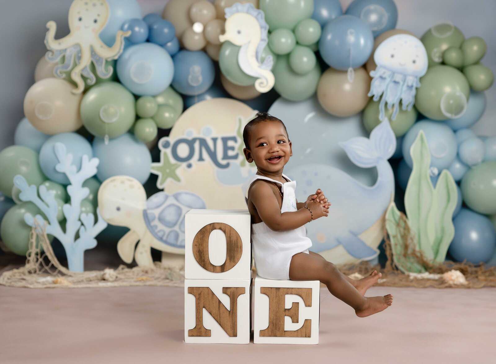 Under the sea set with little boy sitting on ONE blocks and smiling. 