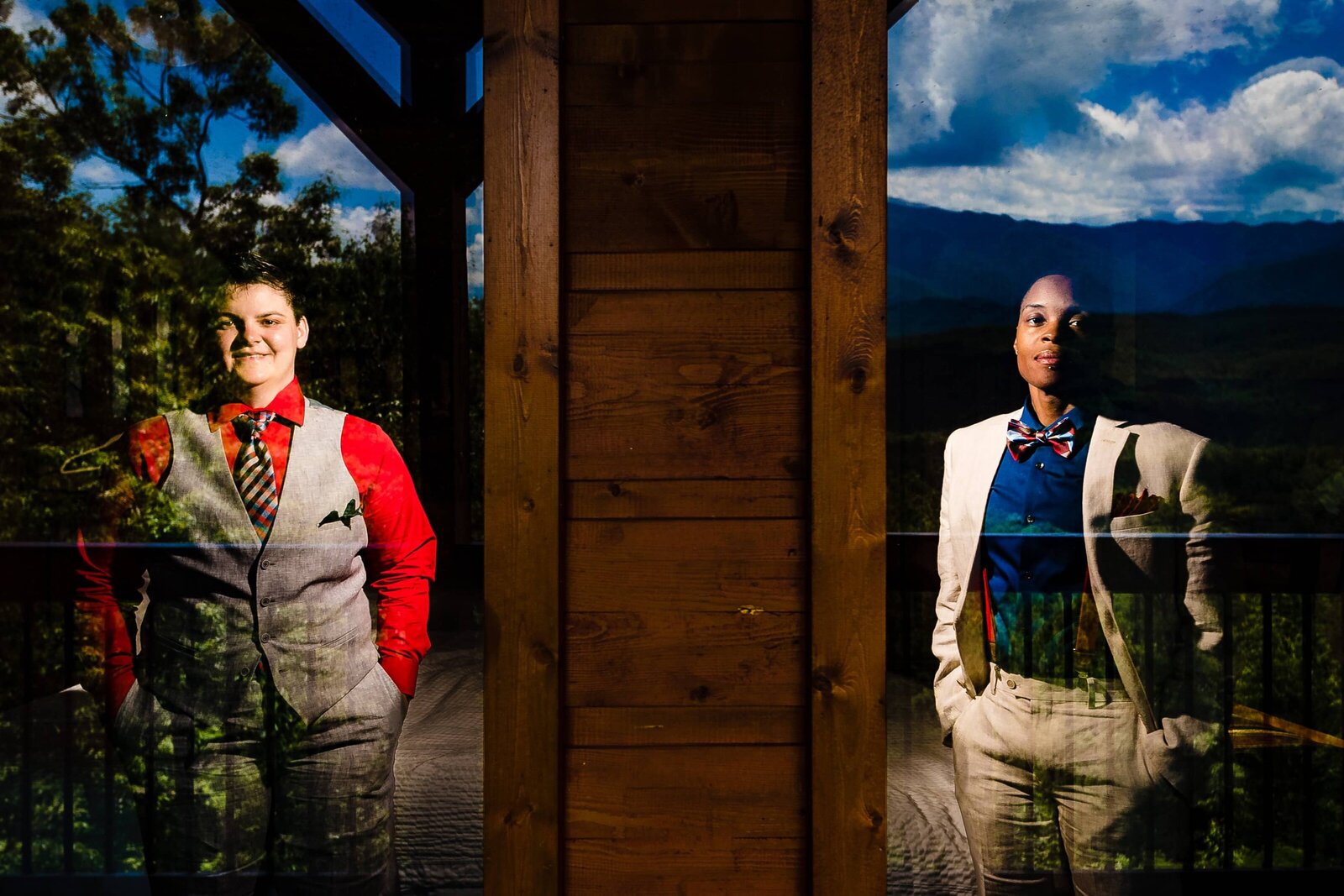 creative wedding photo of a same-sex couple standing behind windows, with the mountains reflected in the glass