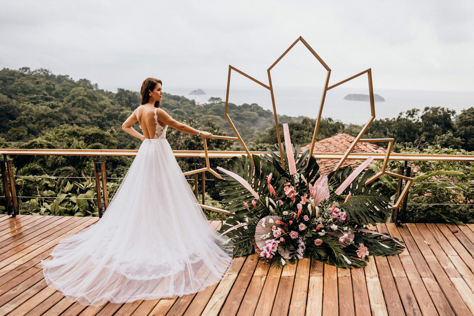 bride posing next to gold and floral archway