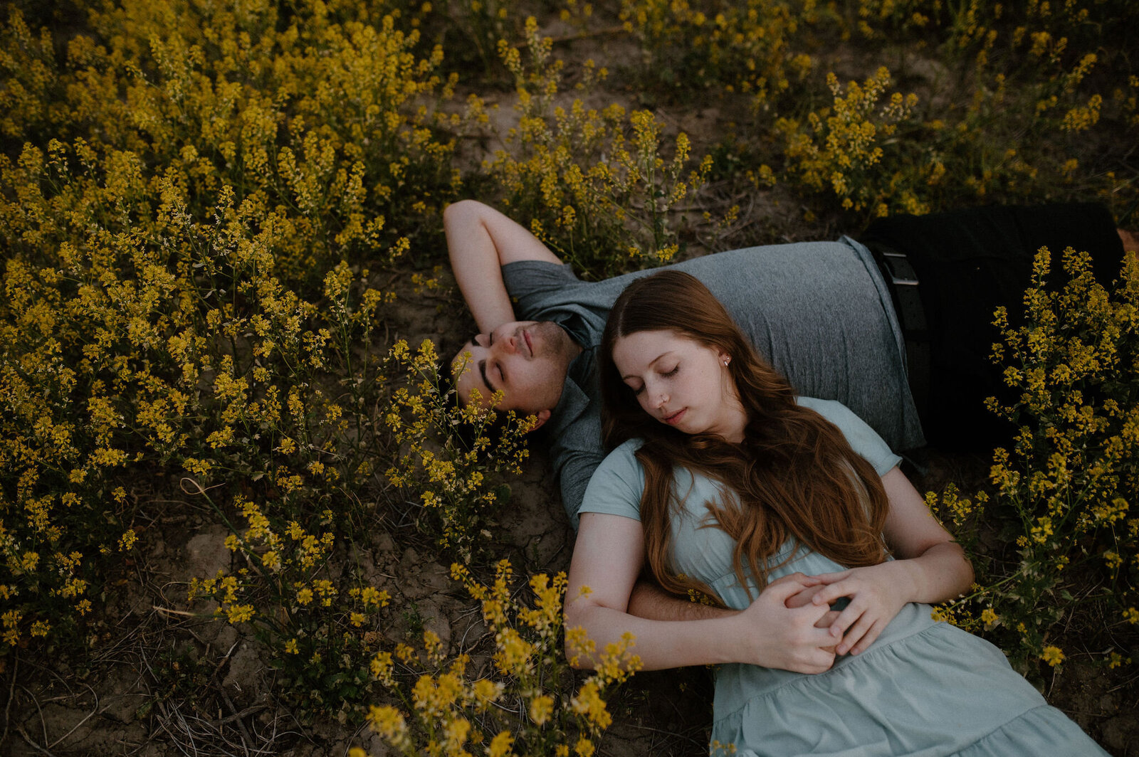 couple laying in a dreamy field of yellow flowers in Gettysburg with moody light
