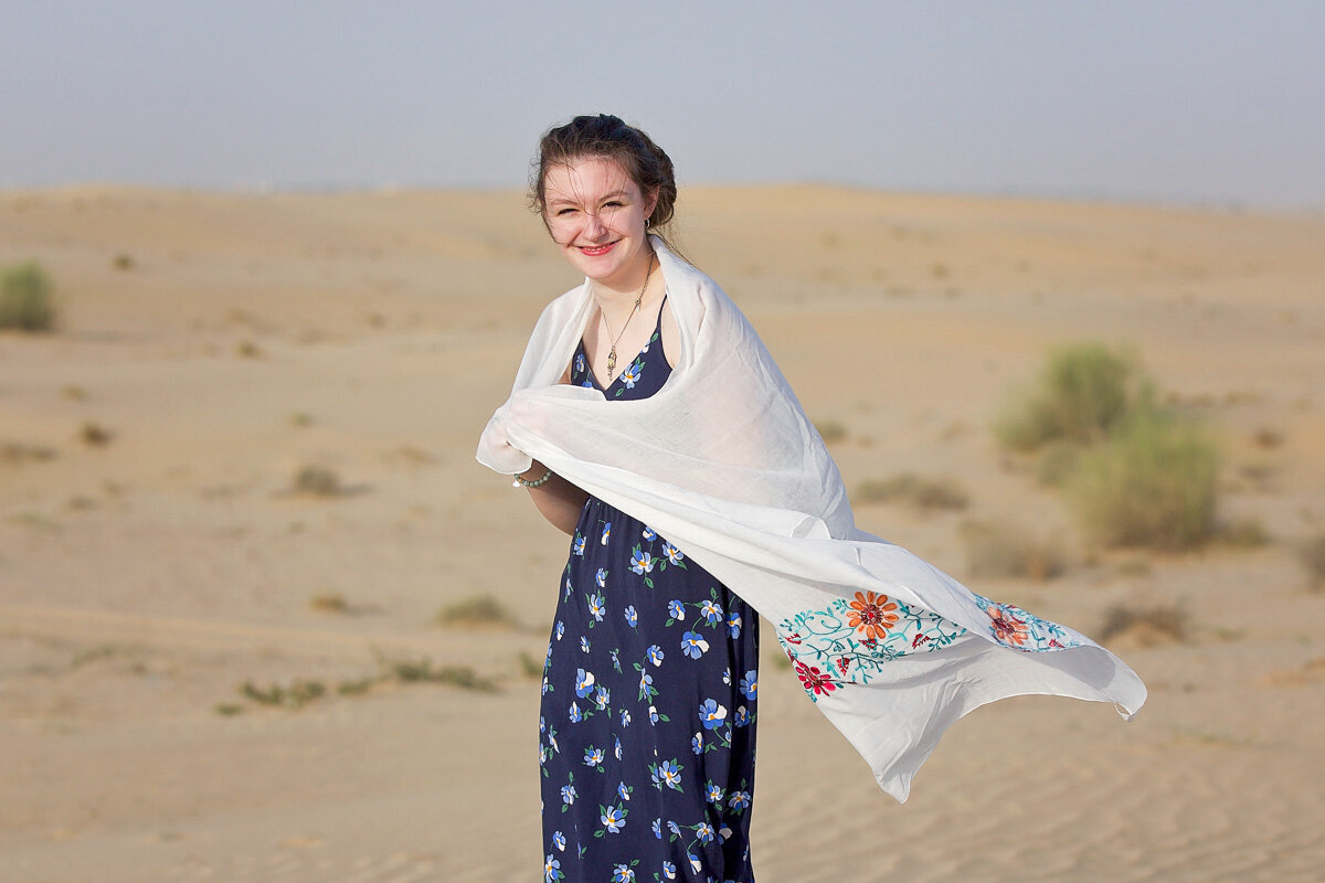 Portrait of a young lady wearing a flower dress and white flower shawl in desert by Alberta family photographer|Yuliia Terziian photography