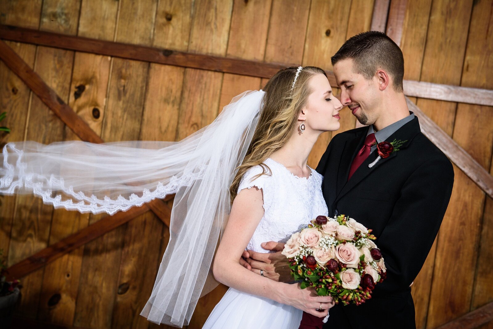 Bride and groom kissing in front of Berry Barn
