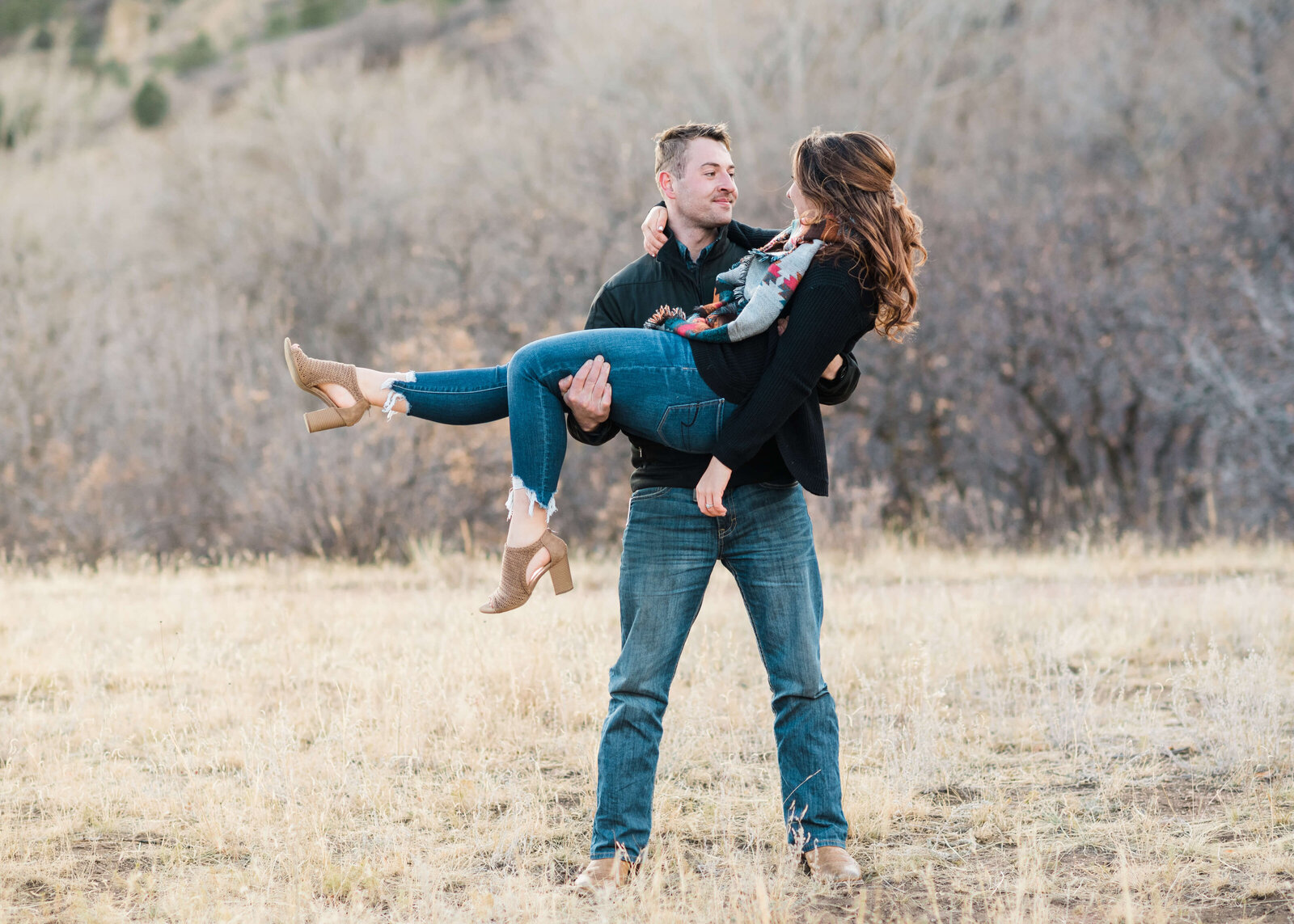 Man holds his fiance in a playful moment during their engagement photo session