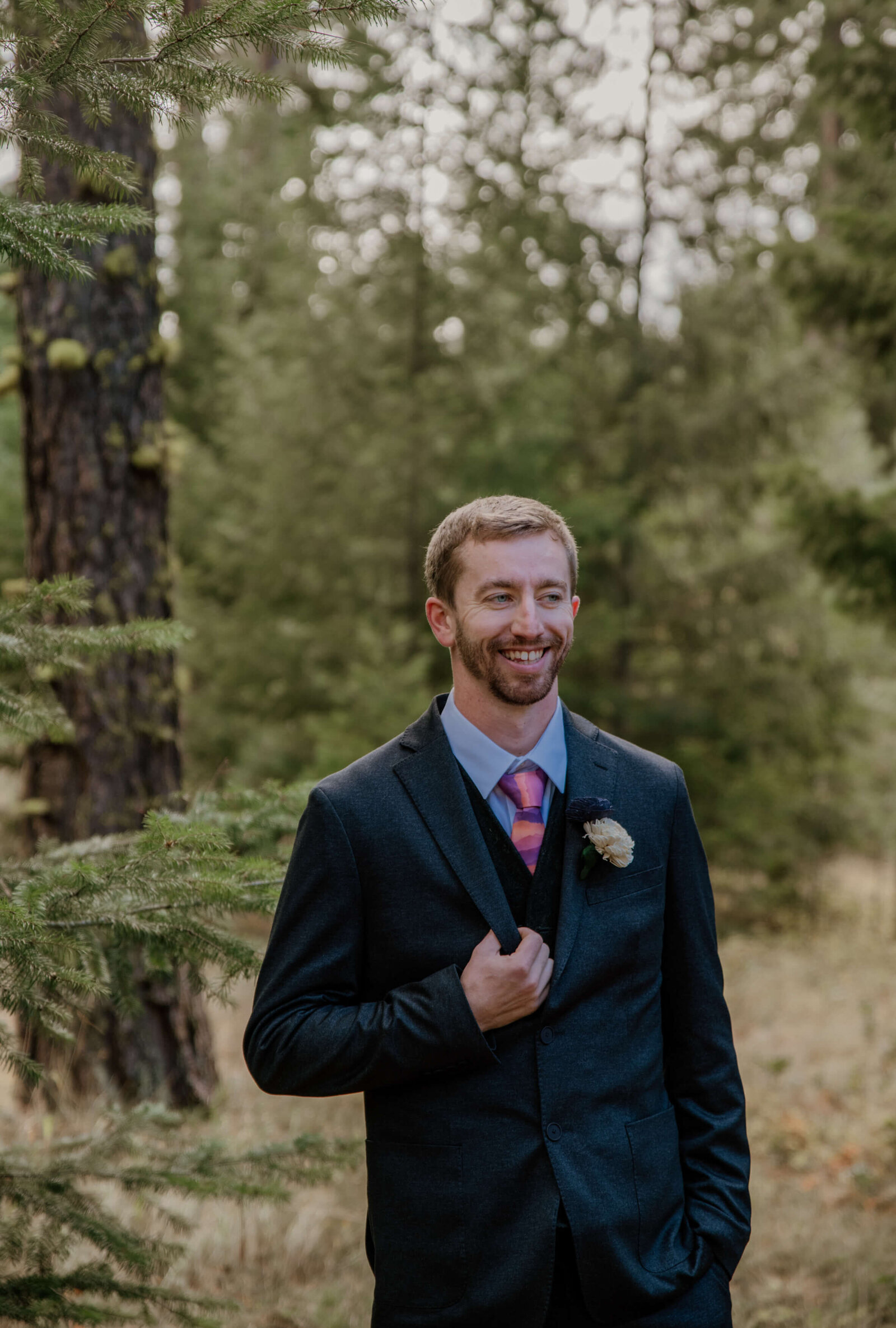 Groom standing in forest.
