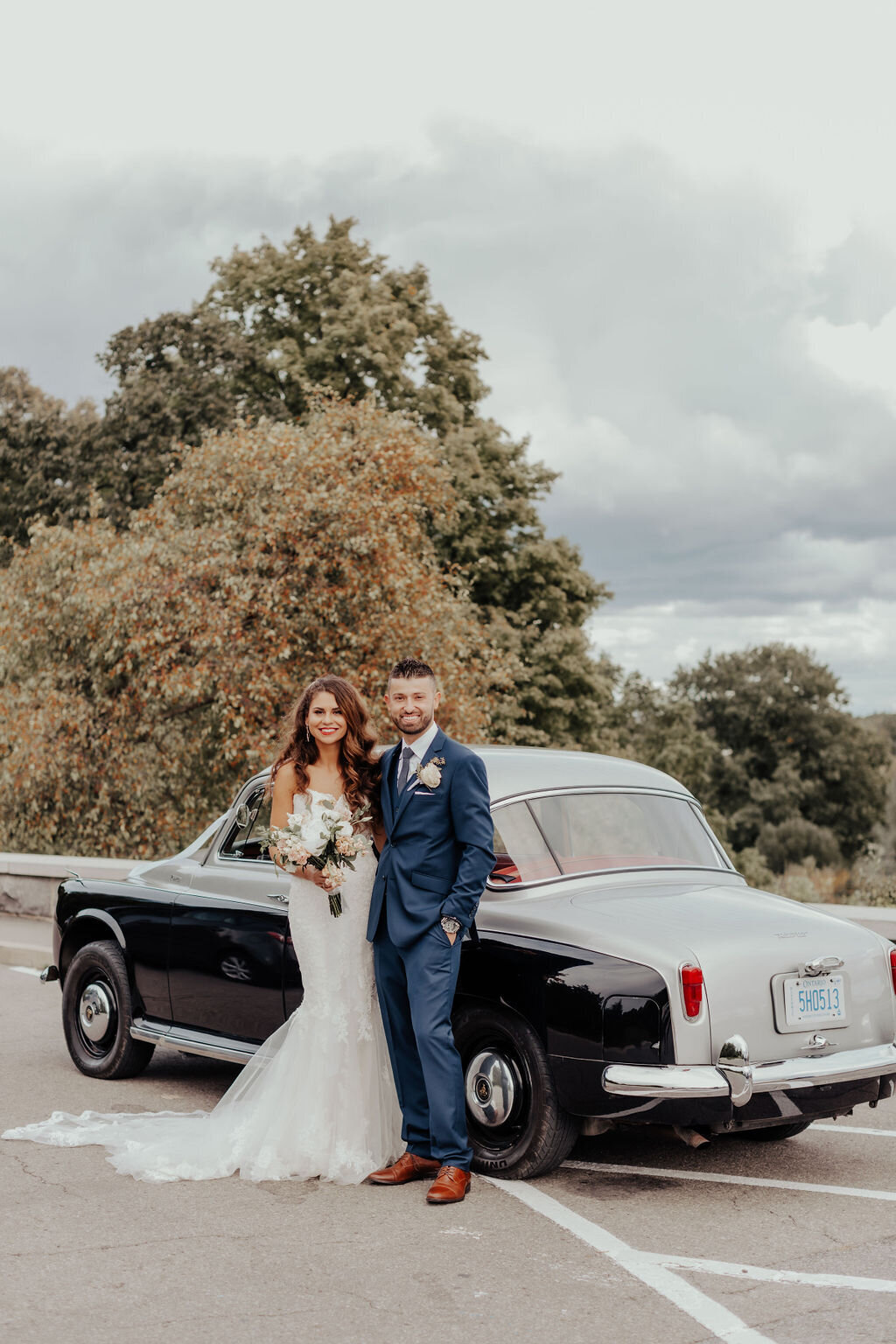 Bride and groom posing with vintage car