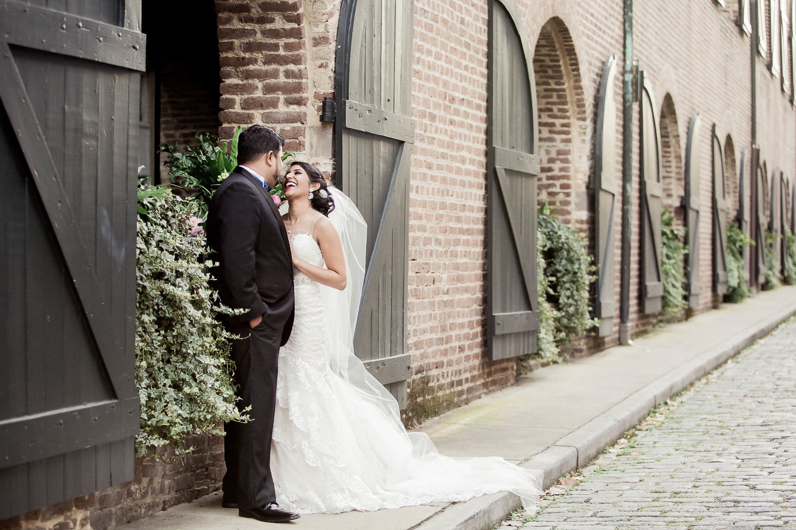 Bride and groom stand by stable doors, French Quarter, South Carolina
