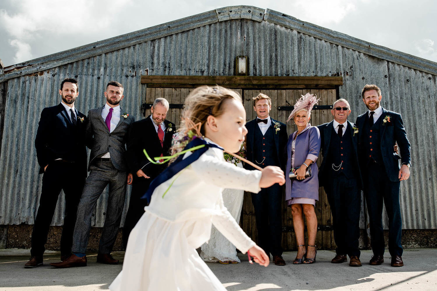 a wedding family portrait is interuppted by the page girl