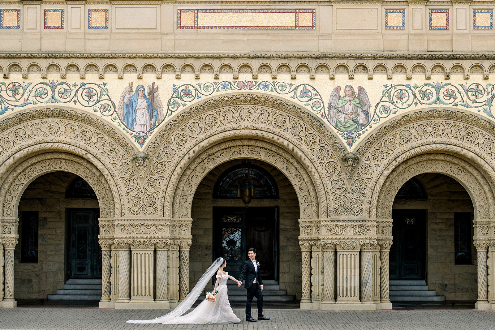 The bride and groom pose in front of the iconic Stanford Memorial Church, capturing the elegance of their wedding day in California.