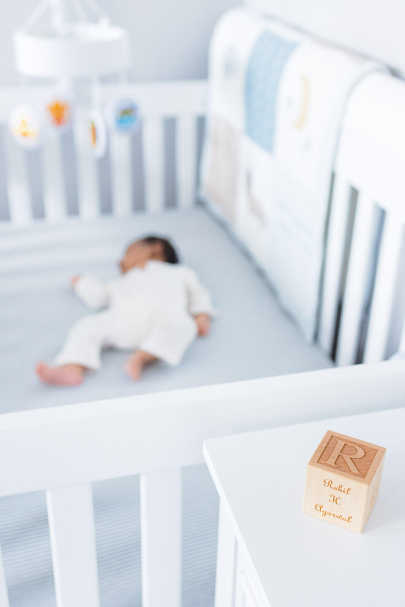 A block with a newborn's birth information on it with the baby in the crib in the background.